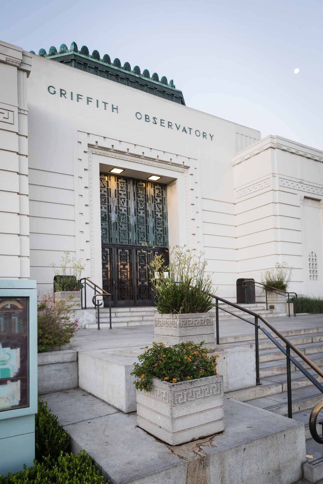 Front entrance, stairs, and Art Deco planters with moon in background at sunrise for an article on where to propose at the Griffith Observatory