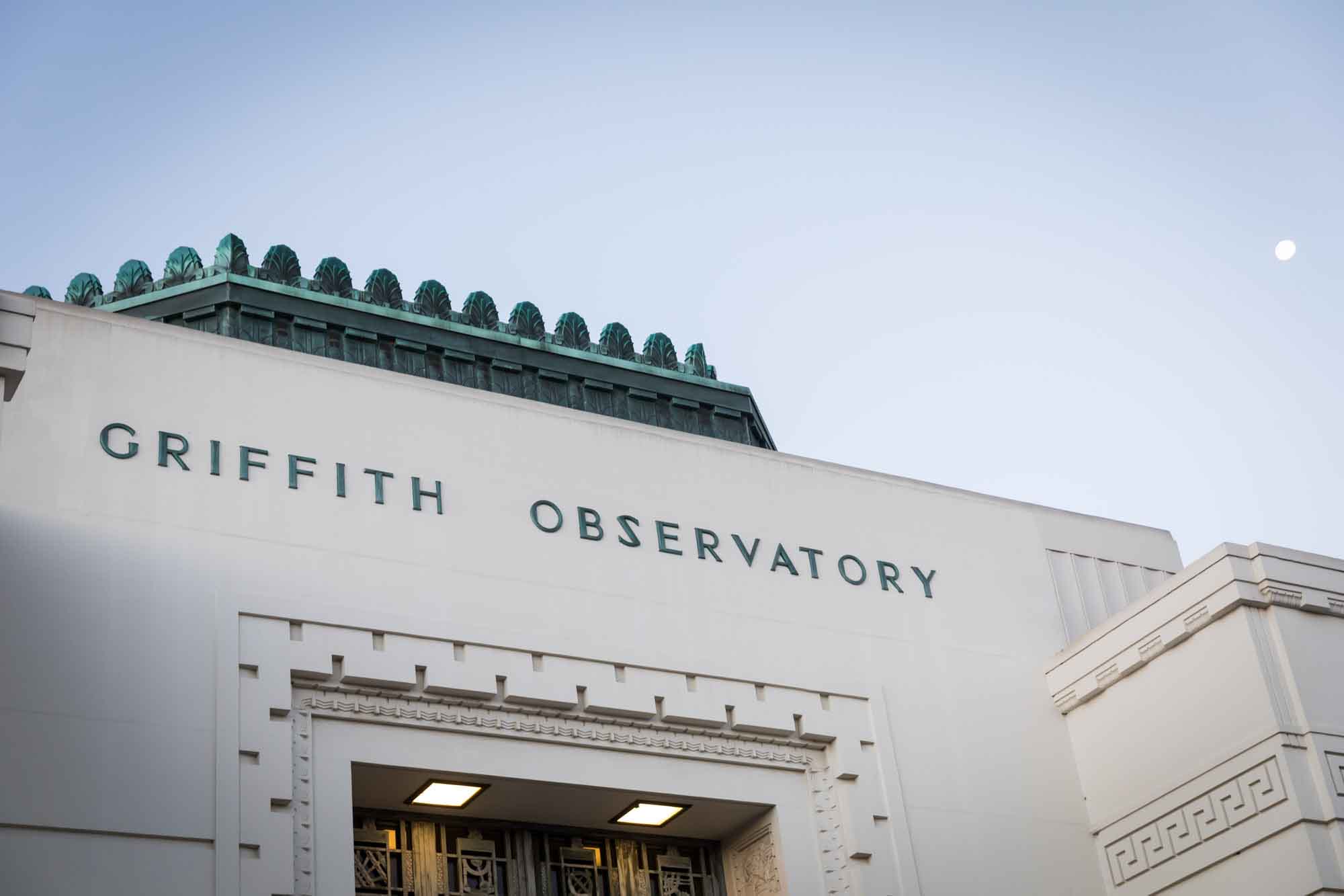 Front entrance to the Griffith Observatory showing copper roof and moon in the background for an article on where to propose at the Griffith Observatory