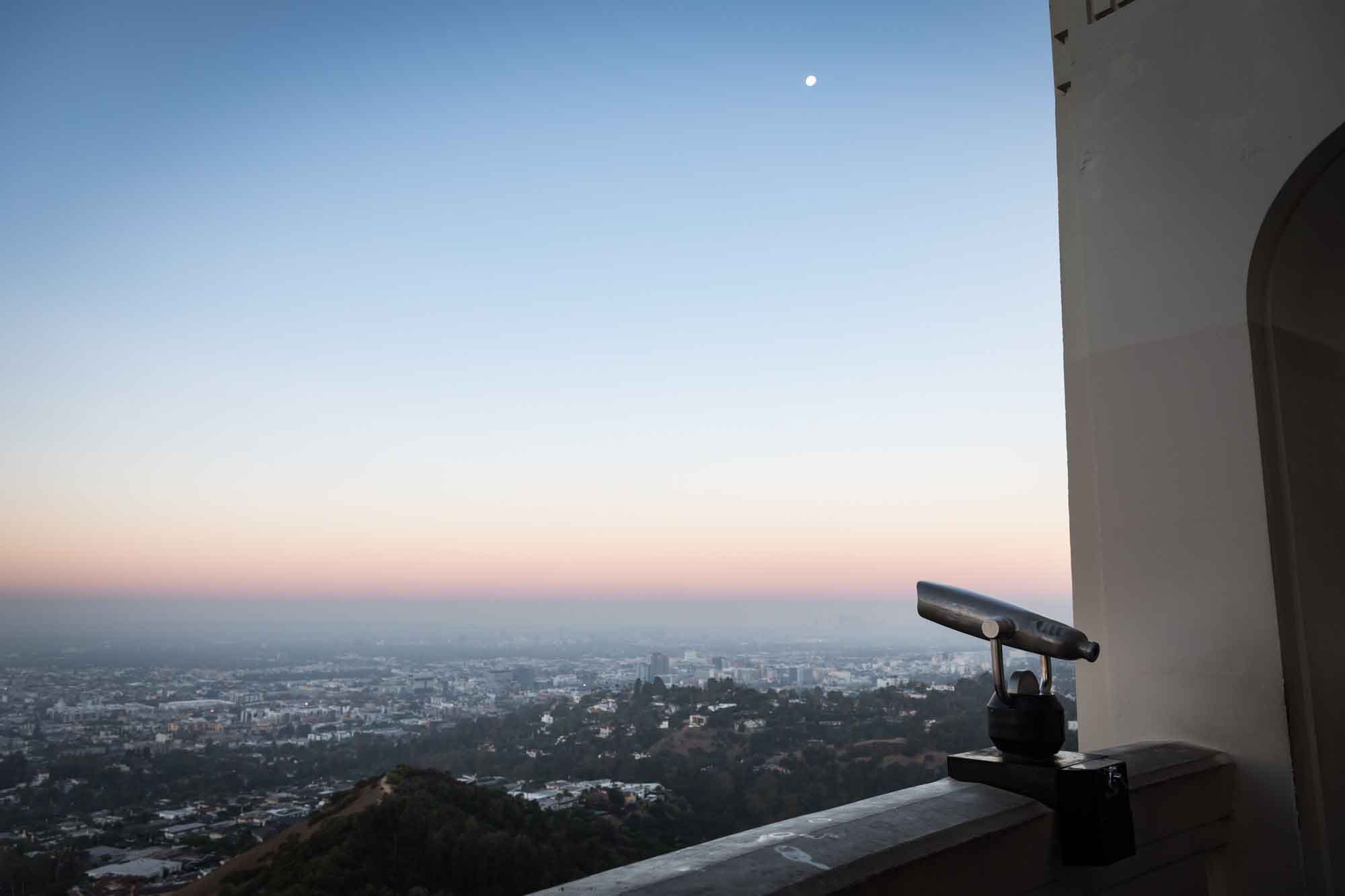 Binoculars on the back of the Griffith Observatory roof with the Los Angeles skyline and moon in the background for an article on where to propose at the Griffith Observatory