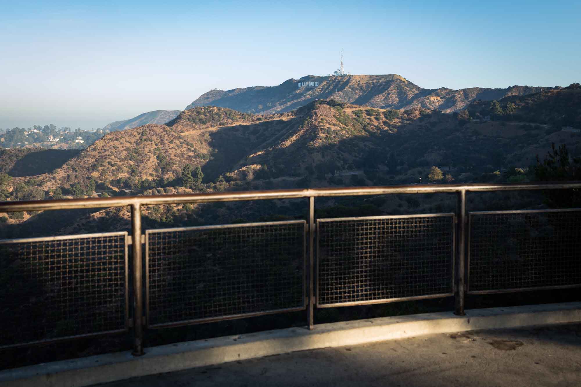 Metal railing on platform with Hollywood Sign and mountains in the background for an article on where to propose at the Griffith Observatory
