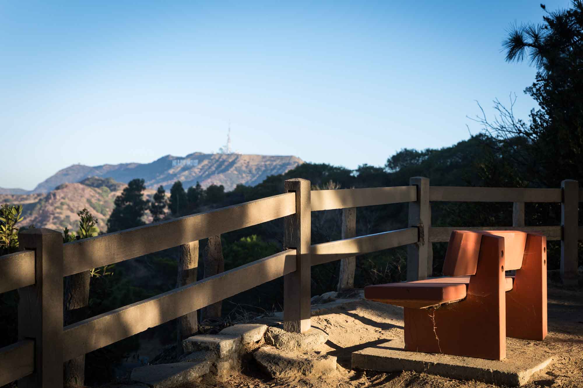 Orange bench in front of wooden railing with Hollywood Sign in the background for an article on where to propose at the Griffith Observatory