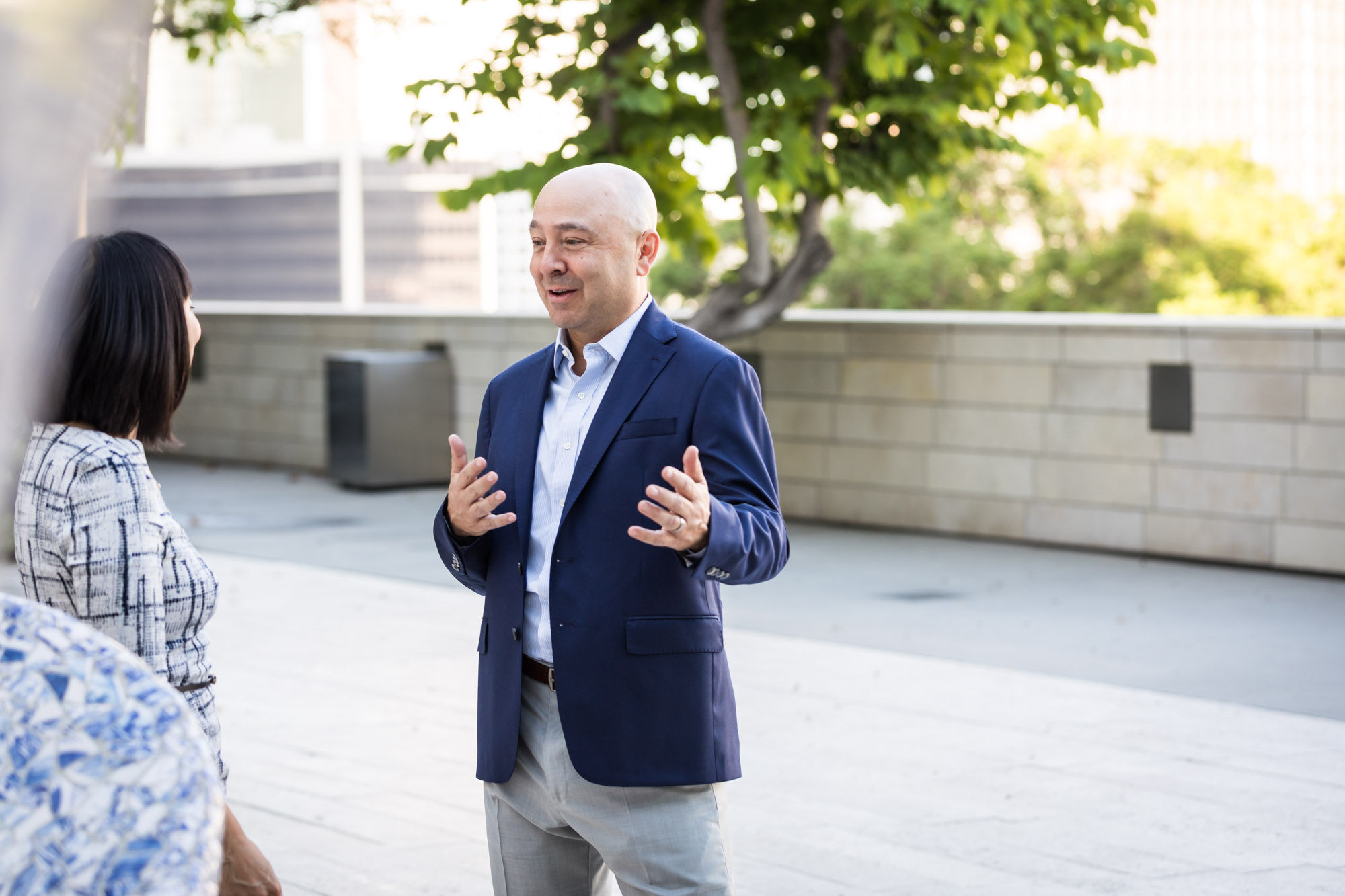 Businessman wearing blue jacket and khaki pants walking and talking with Asian American female colleague wearing dress in Blue Ribbon Garden for an article on how to prepare for a branding photo shoot