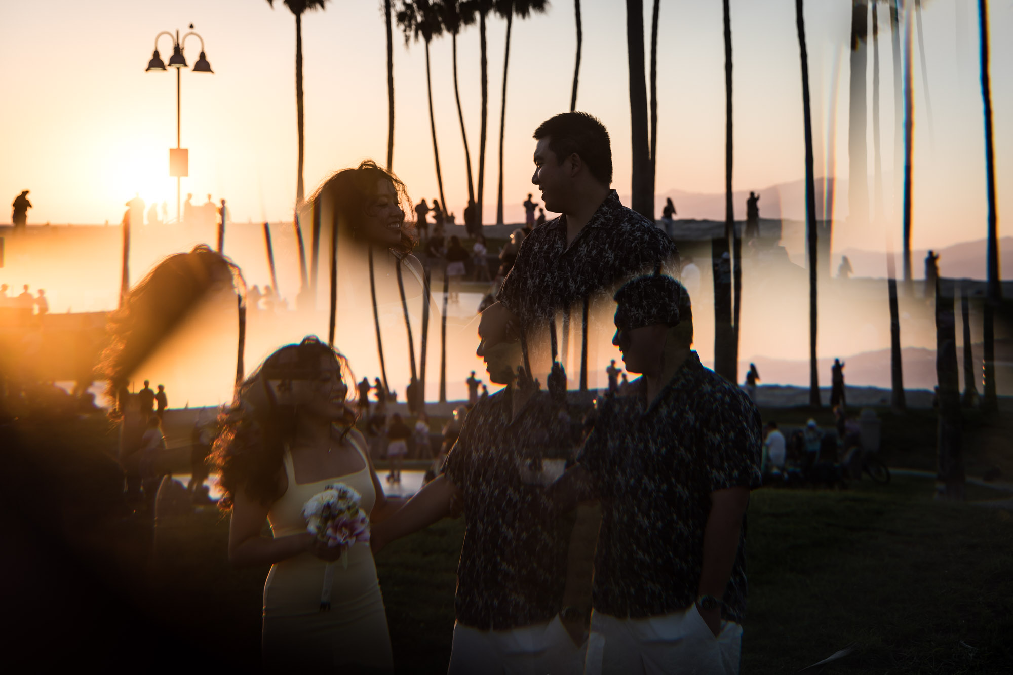 Prism photo of woman holding flower bouquet and man at sunset with palm trees in background