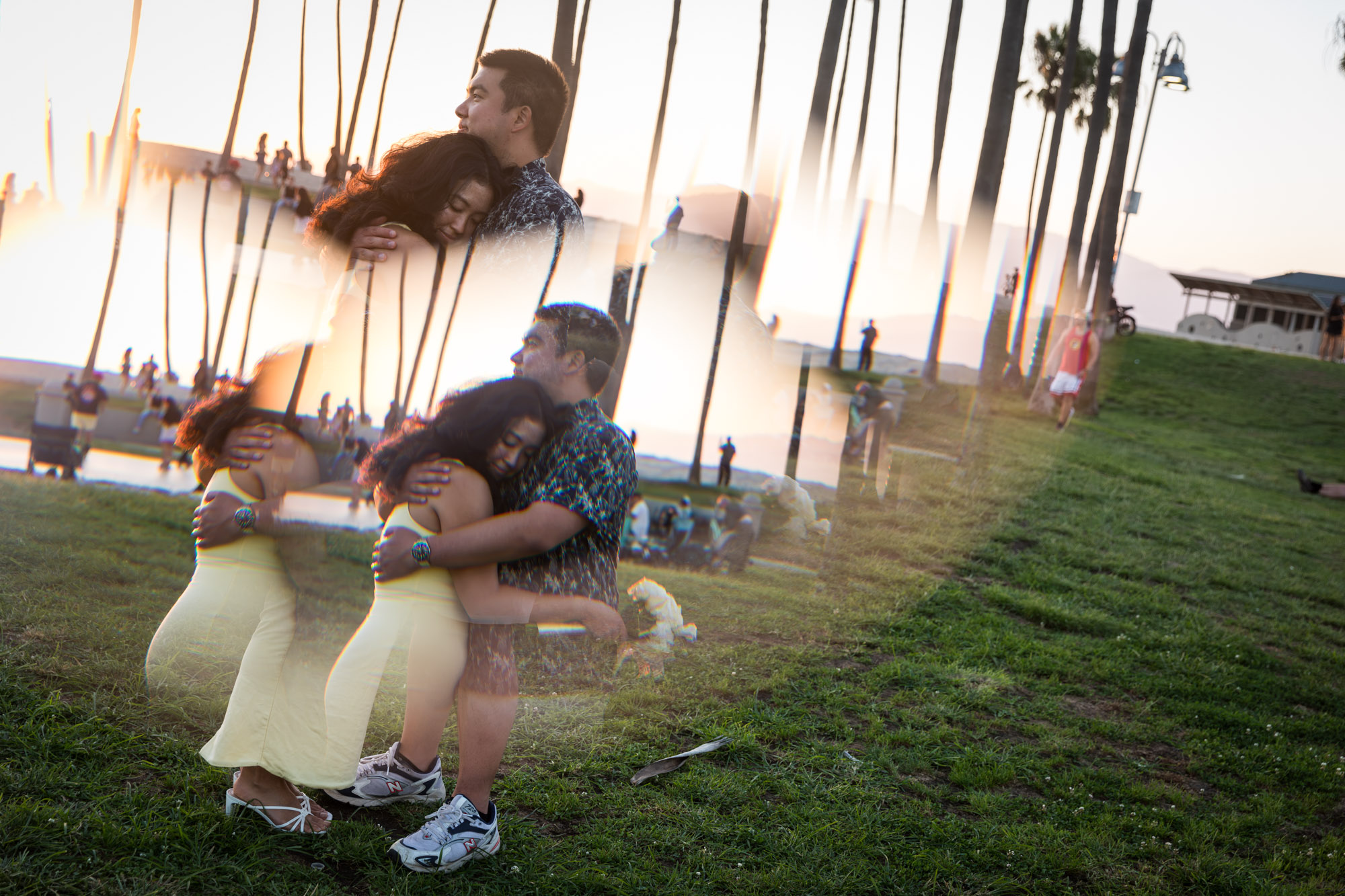 Prism photo of woman holding flower bouquet and man hugging at sunset with palm trees in background