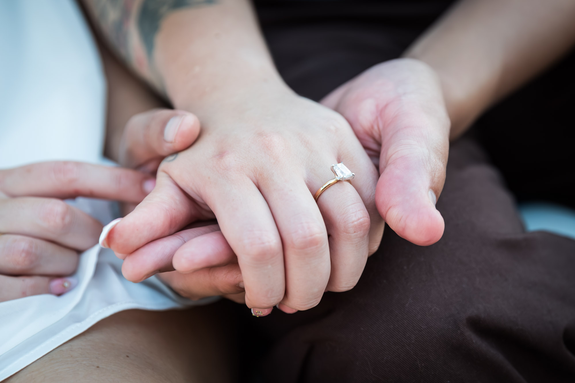 Close up of man holding woman's hand wearing engagement ring