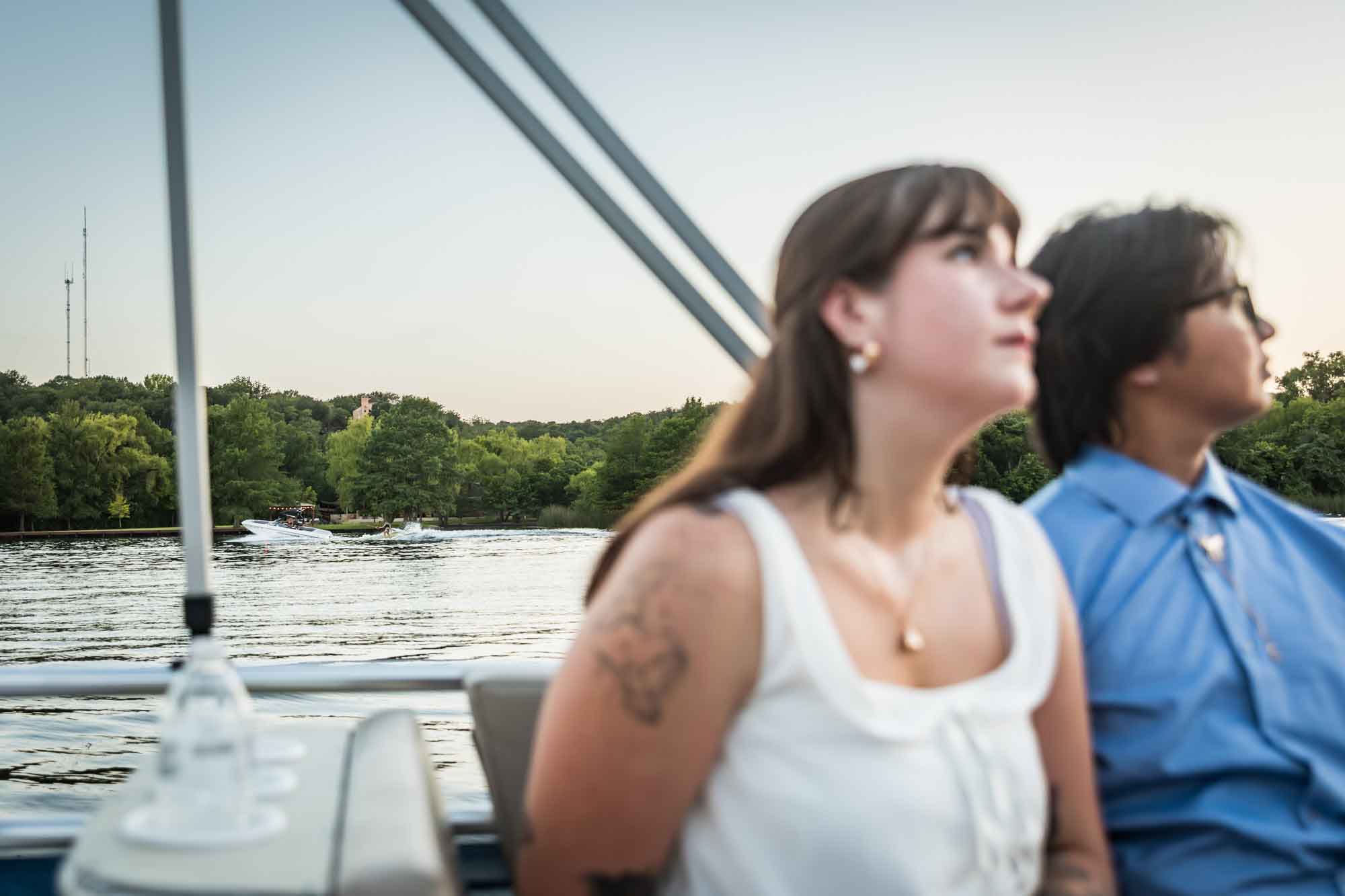 Boat in water behind man wearing blue shirt and woman wearing sleeveless white shirt