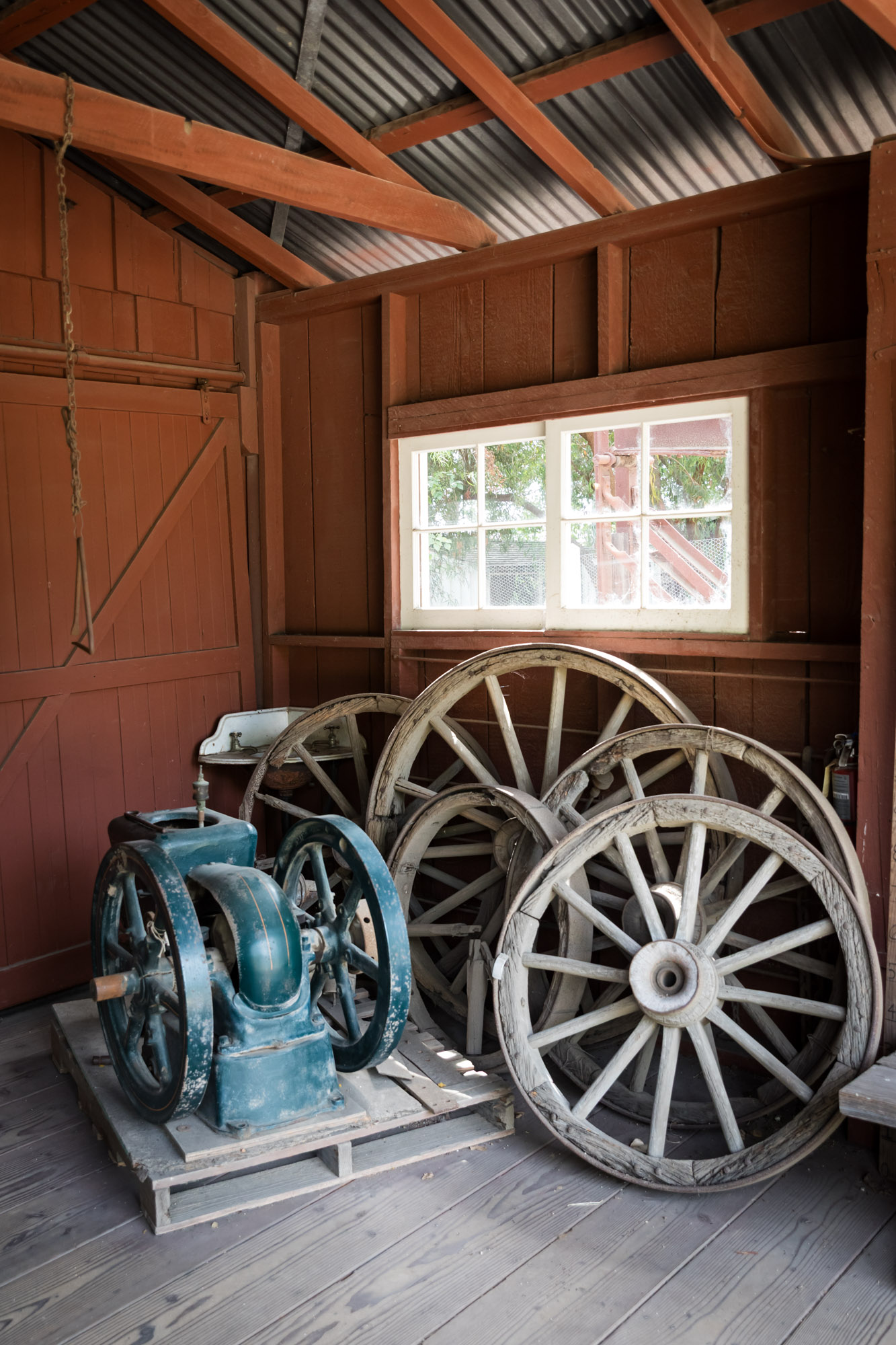 Old farming equipment and stagecoach wheels propped up against a barn wall at Rancho Los Alamitos for an article on where to propose in Long Beach