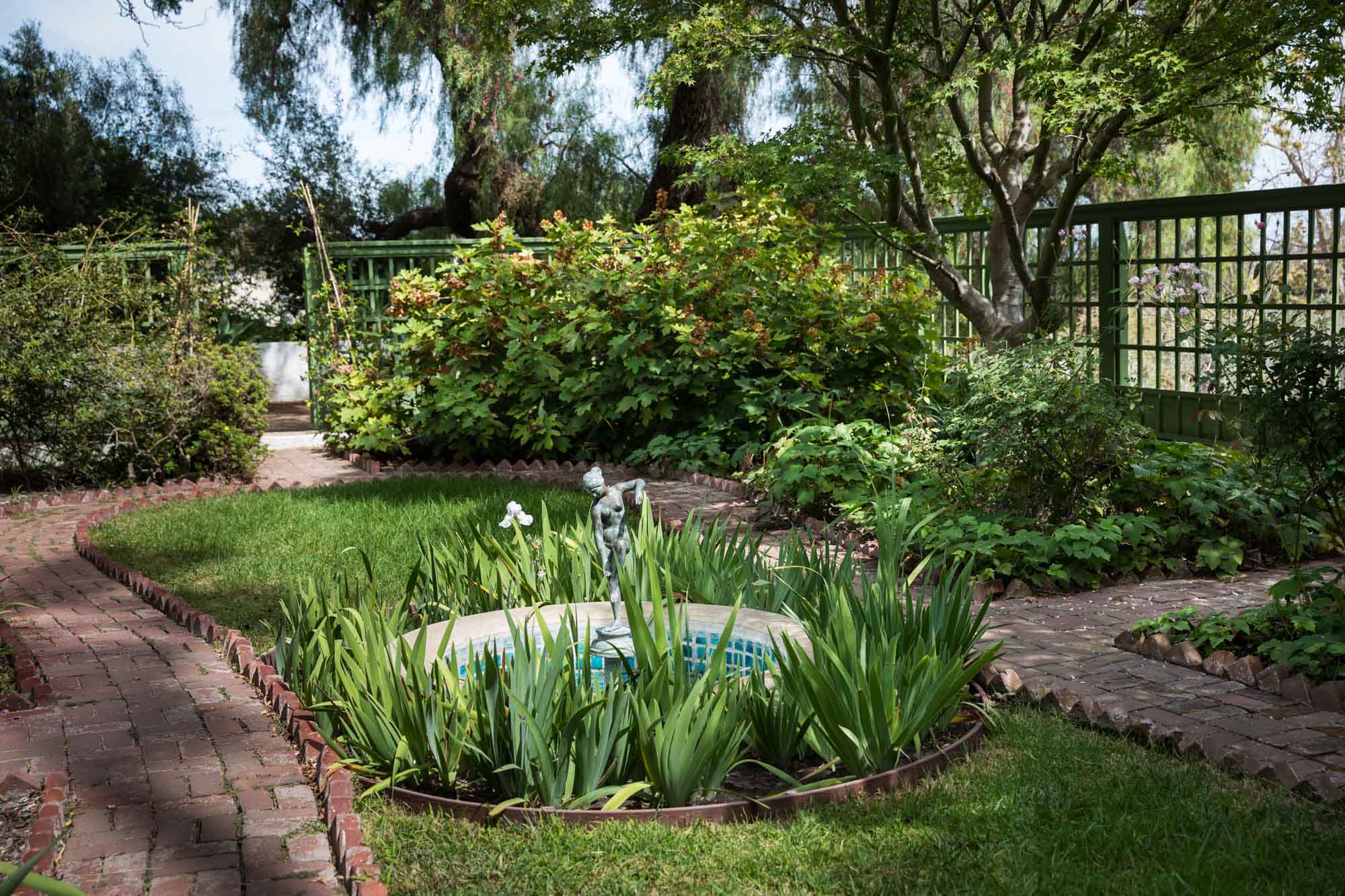 A small bronze statue in the middle of a small pond surrounded by irises in the Friendly Garden in Rancho Los Alamitos for an article on where to propose in Long Beach