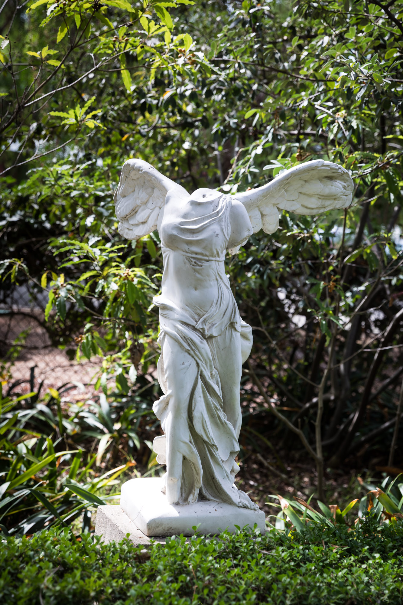 A replica of the Winged Victory of Samothrace statue surrounded by trees and bushes at Rancho Los Alamitos for an article on where to propose in Long Beach