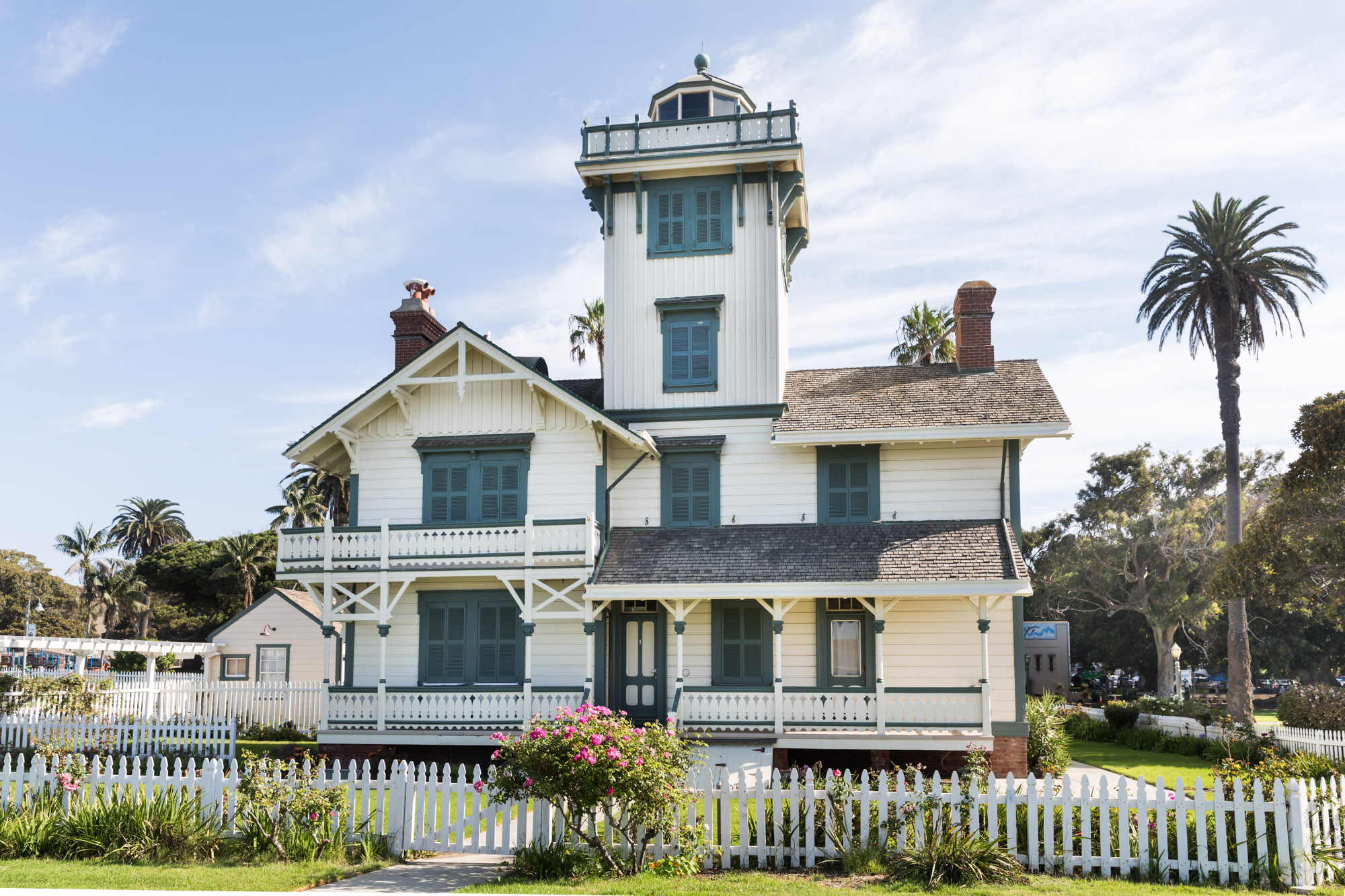 Point Fermin Lighthouse with white gate and rose bush in front for an article on where to propose in Long Beach