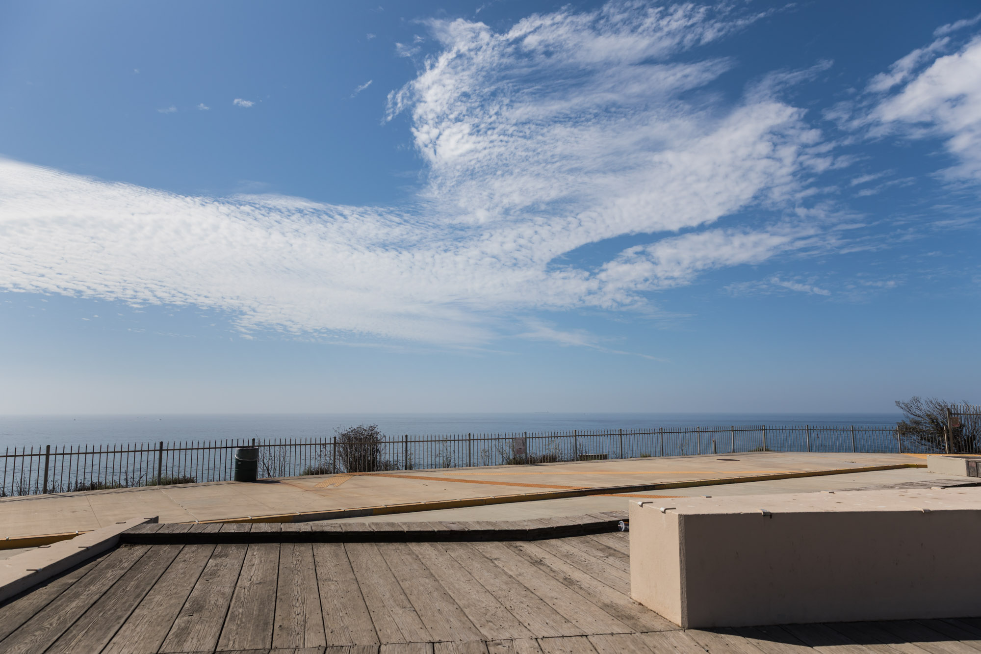 Wooden slat platform with black gate and Pacific Ocean in the background at the corner of Bluffs Place and Pacific Avenue for an article on where to propose in Long Beach