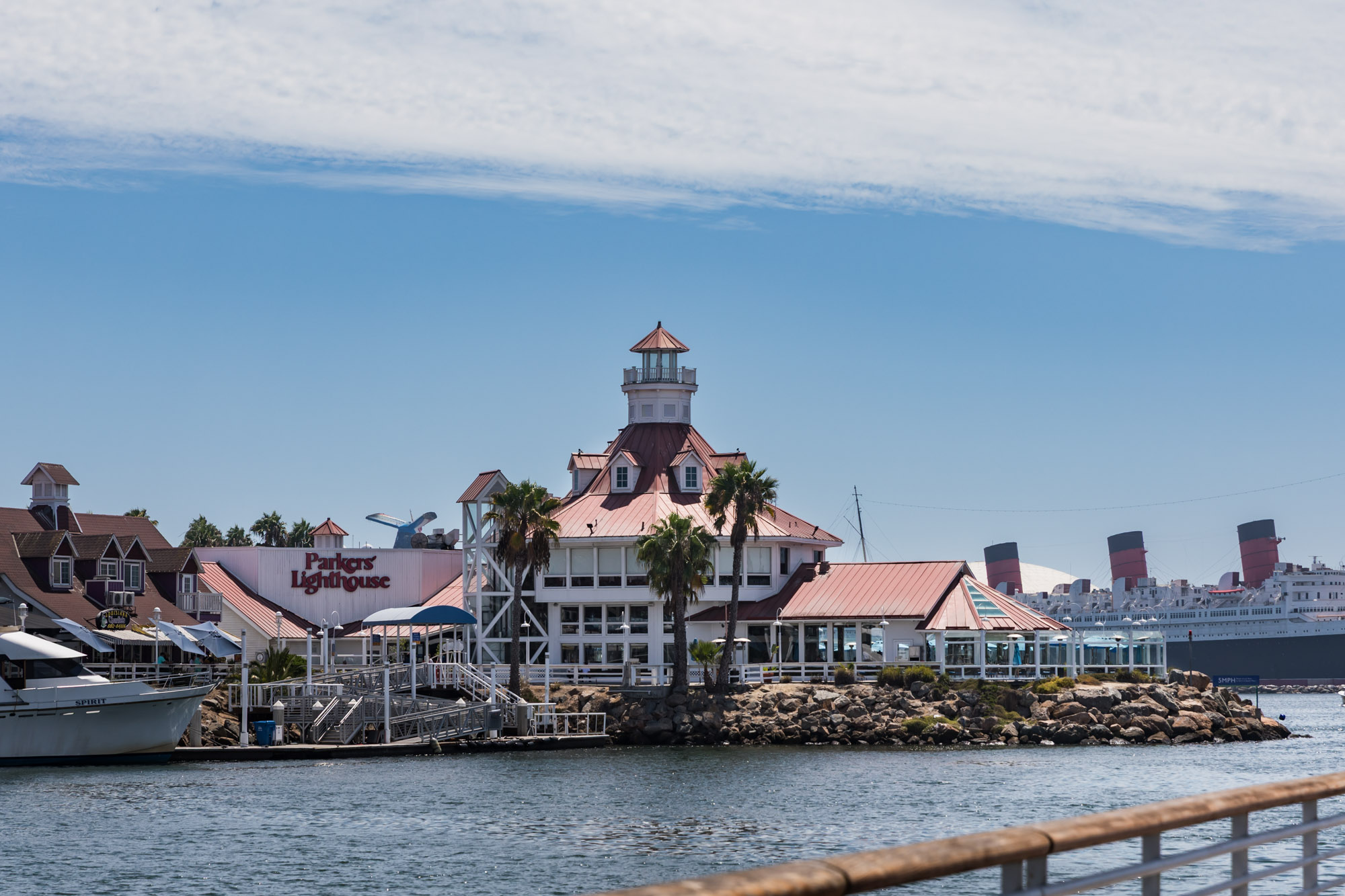 Parks' Lighthouse Restaurant sitting on a rock base in Shoreline Marina in the water with clouds overhead for an article on where to propose in Long Beach
