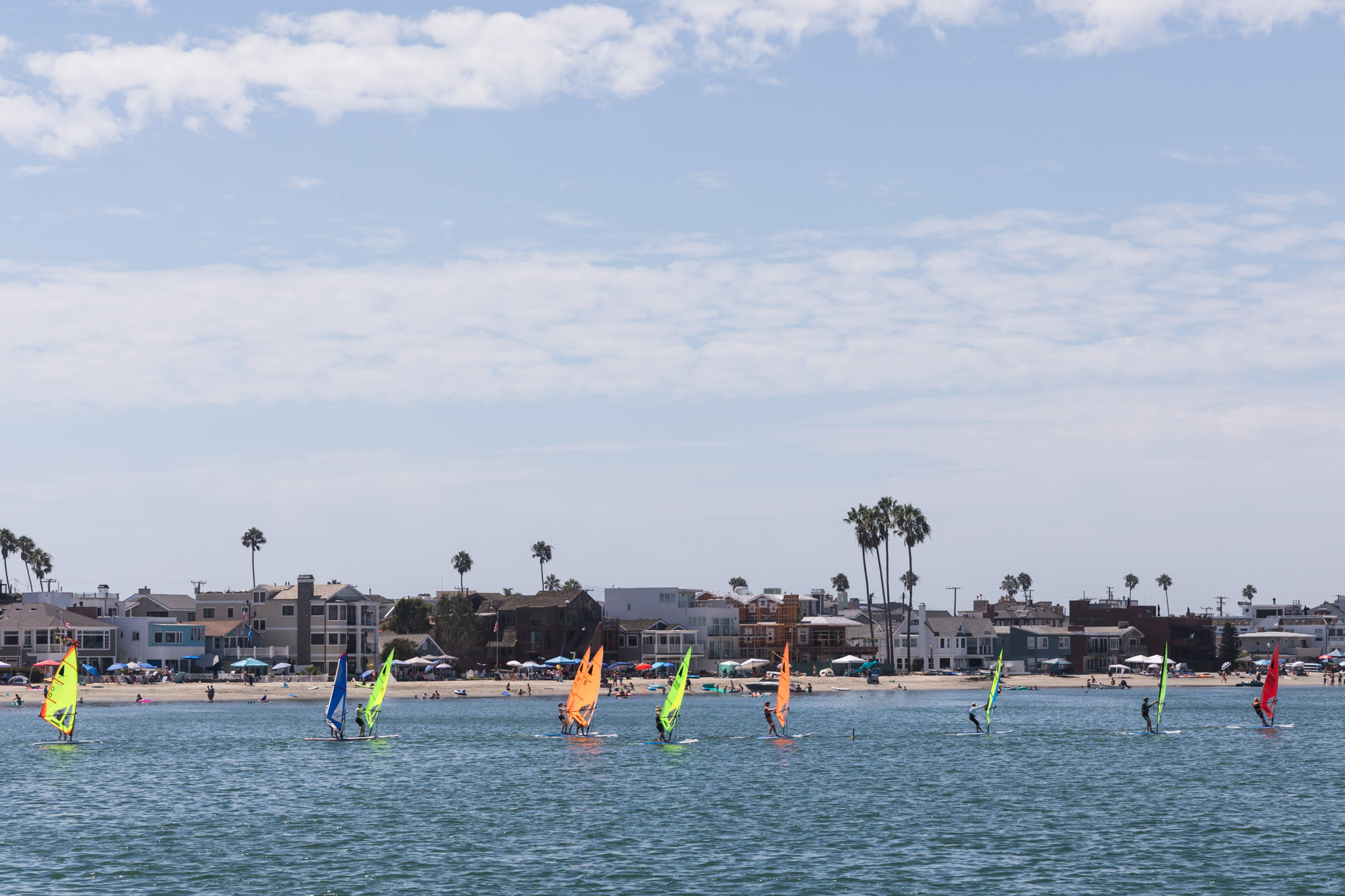 10 colorful wind surfers in the water in front of Alamitos Park for an article on where to propose in Long Beach