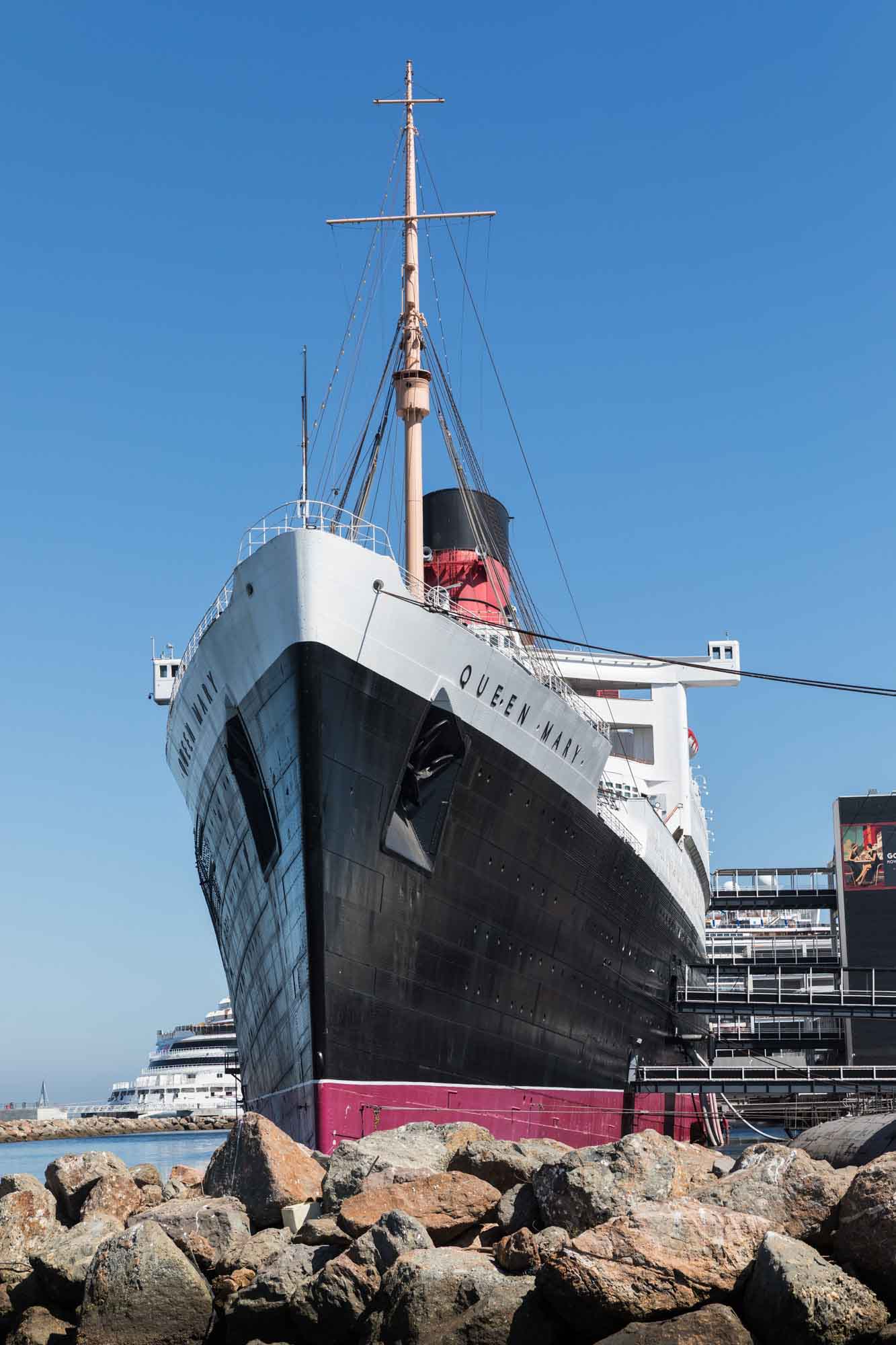 A head-on view of the Queen Mary ocean liner with a rock jetty in front for an article on where to propose in Long Beach