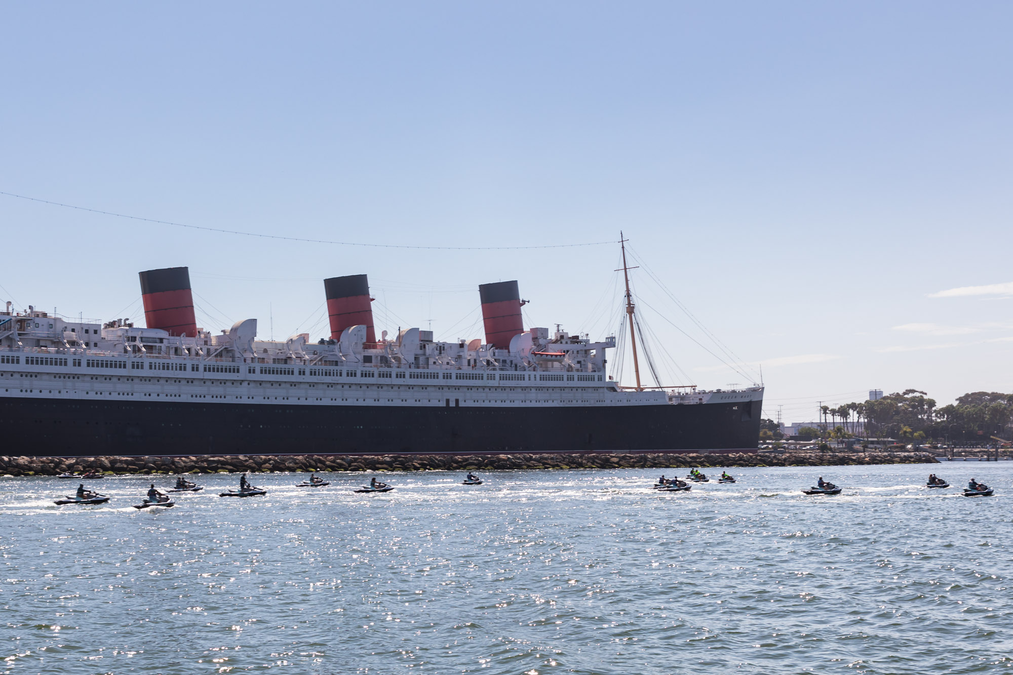 14 people on jet skis riding past the Queen Mary for an article on where to propose in Long Beach