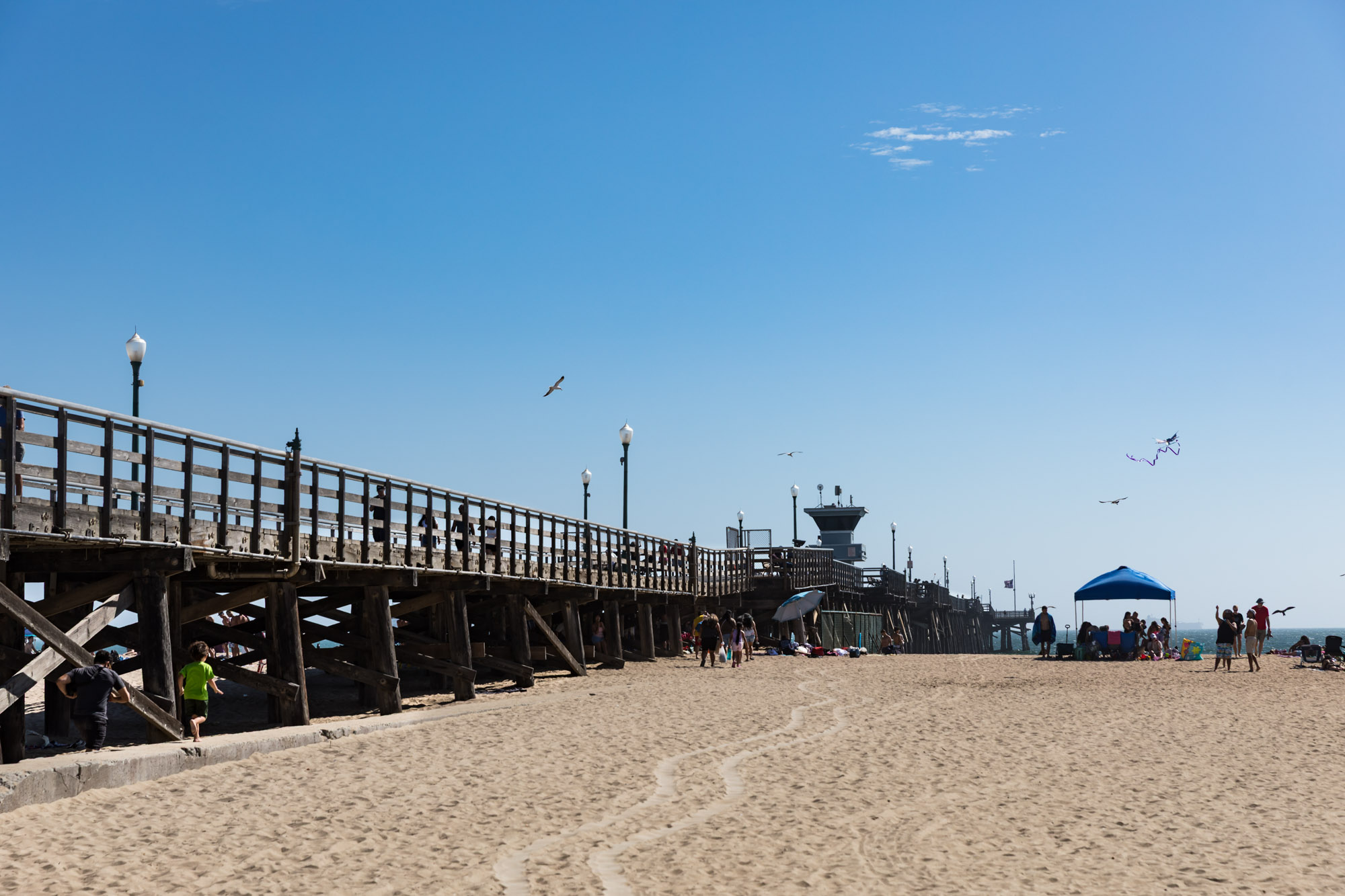 Seal Beach Municipal Pier with people enjoying the beach and flying kites for an article on where to propose in Long Beach