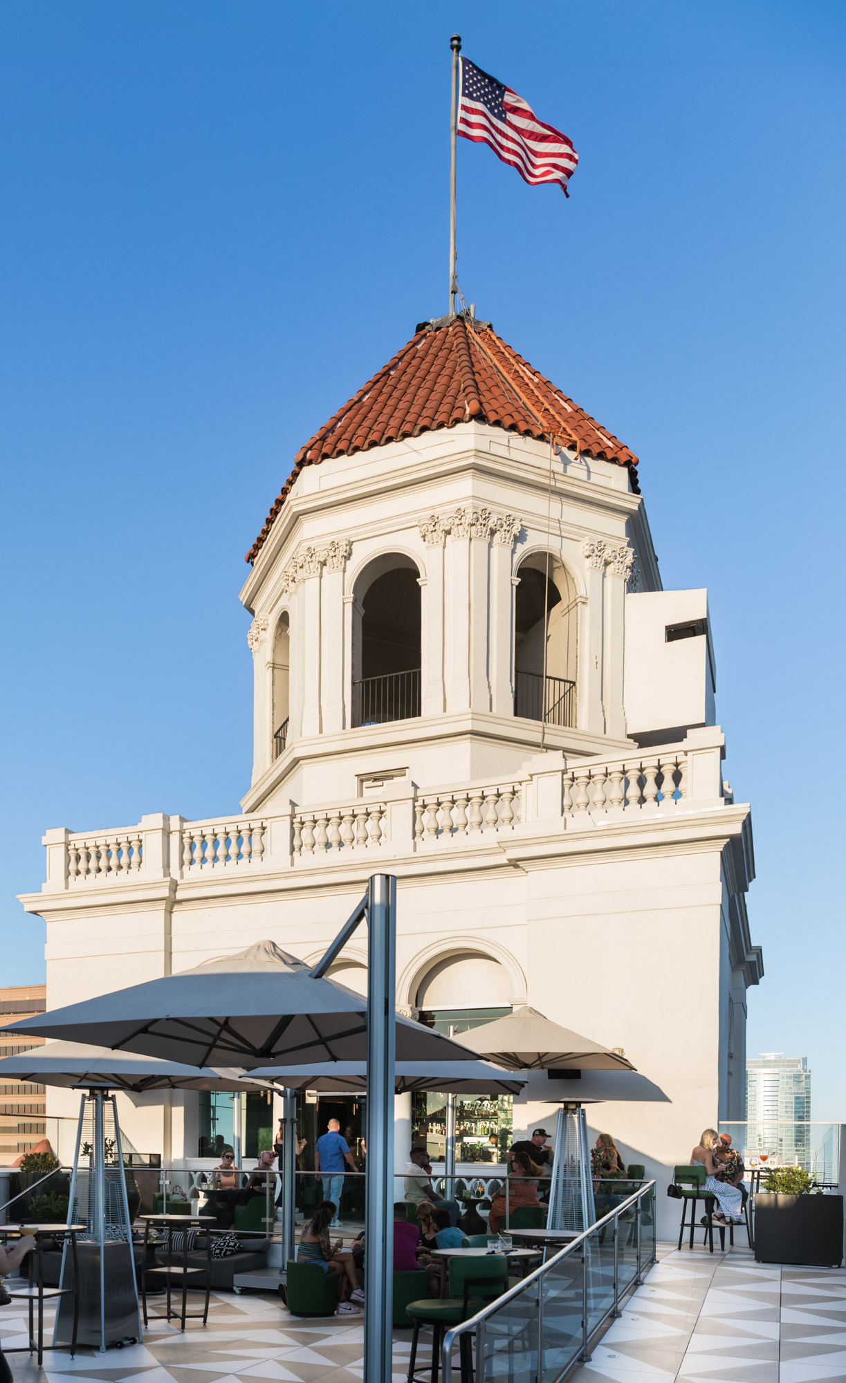 Exterior of Halo Rooftop Bar with top of the Fairmont Breakers Long Beach Hotel and American flag waving for an article on where to propose in Long Beach