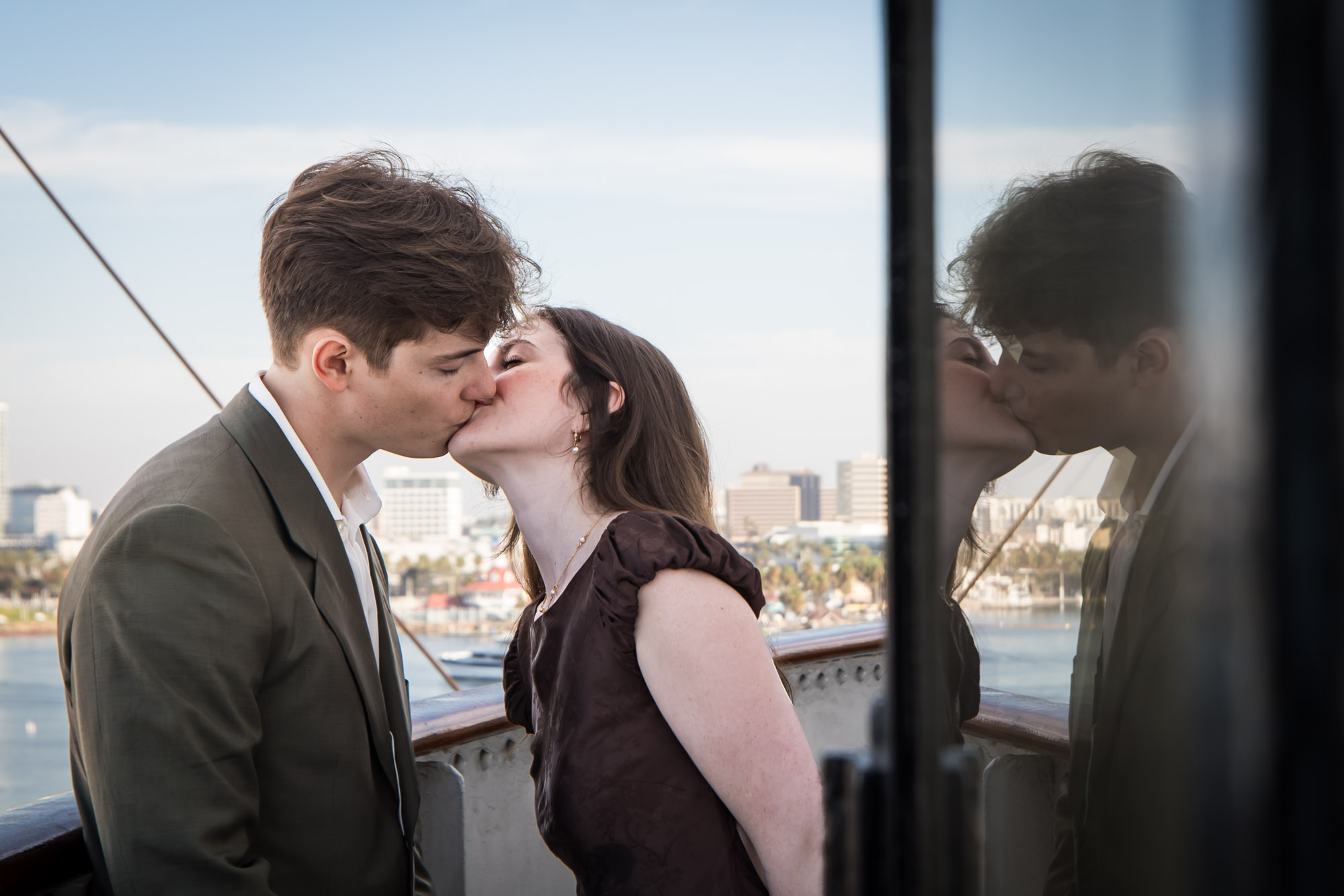 Couple kissing on the Bridge walkway, with their reflection in the wheelhouse window, during a Queen Mary photo shoot