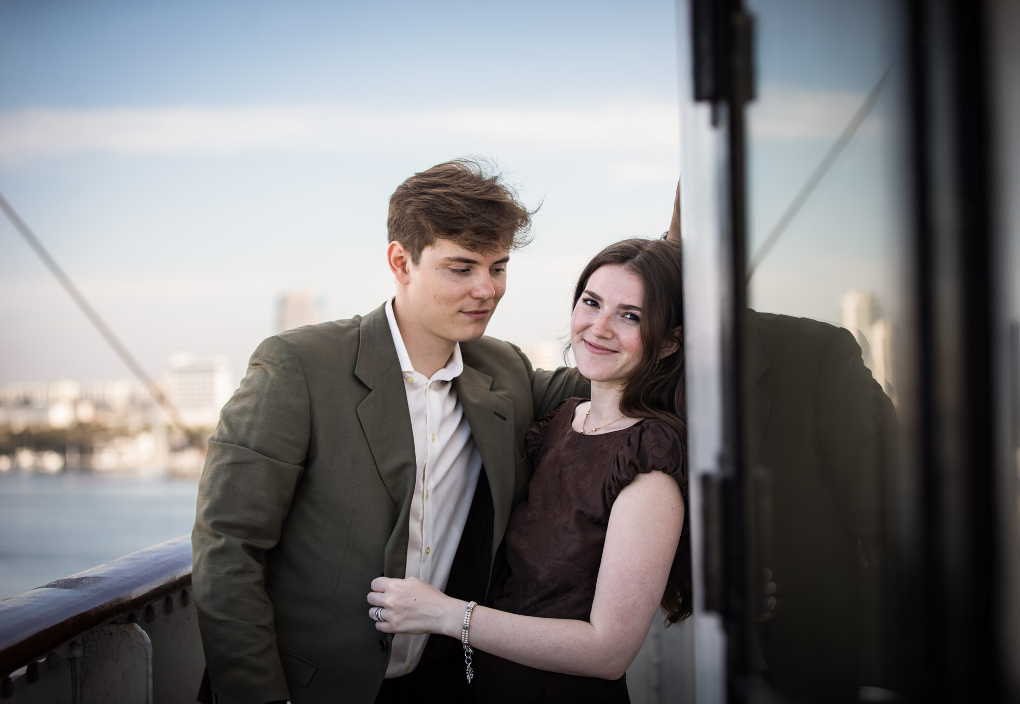 Woman smiling at the camera as the man looks down at her, a Bridge walkway portrait from their Queen Mary photo shoot