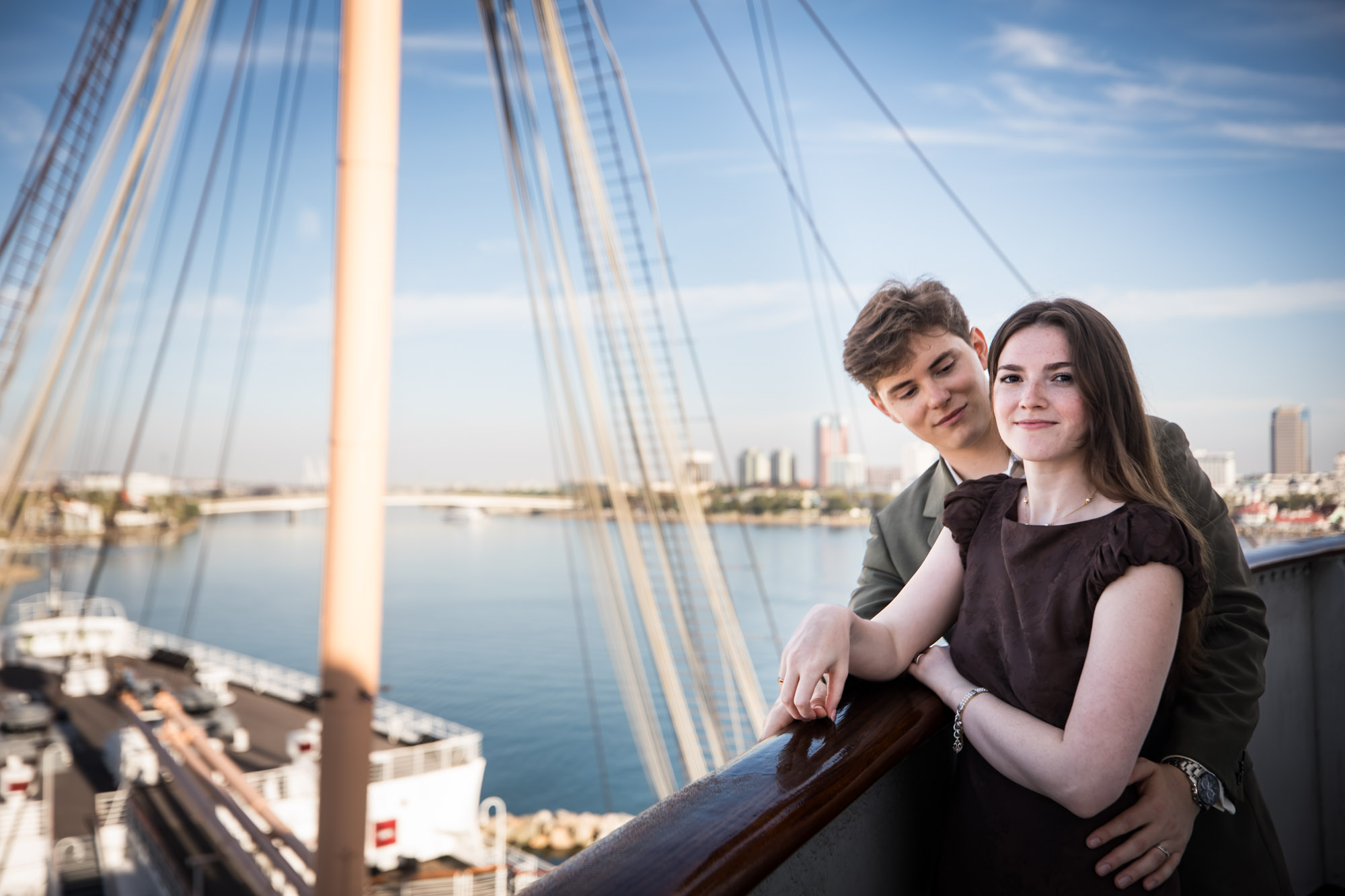 Couple at the Bridge wing rail with the mast, rigging, and bow behind them, a favorite spot for a Queen Mary photo shoot