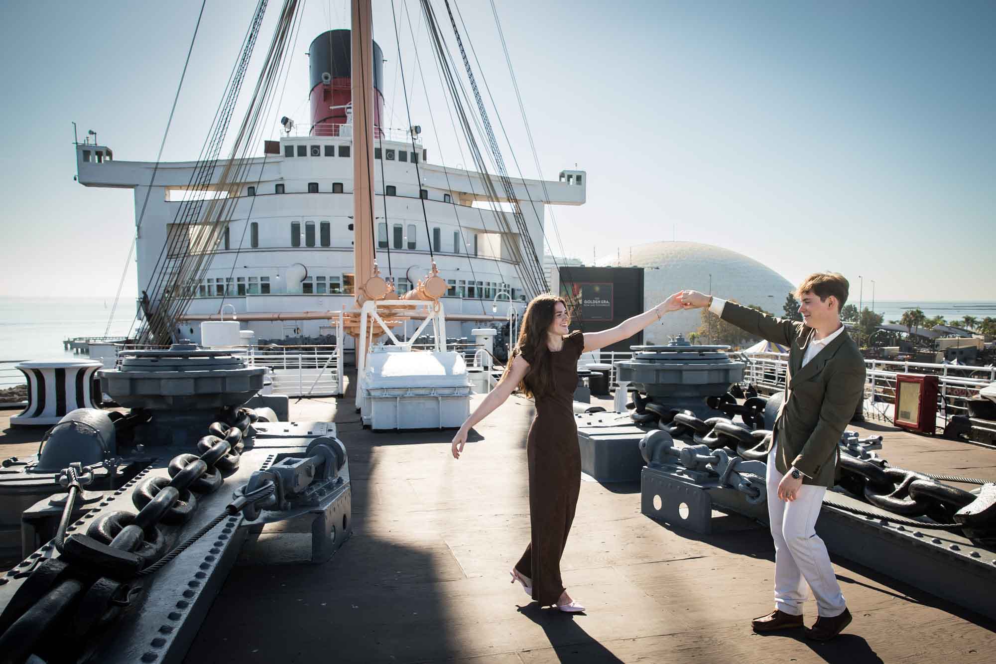 Couple dancing and twirling on the bow deck among anchor chains and capstans, by a Long Beach photographer