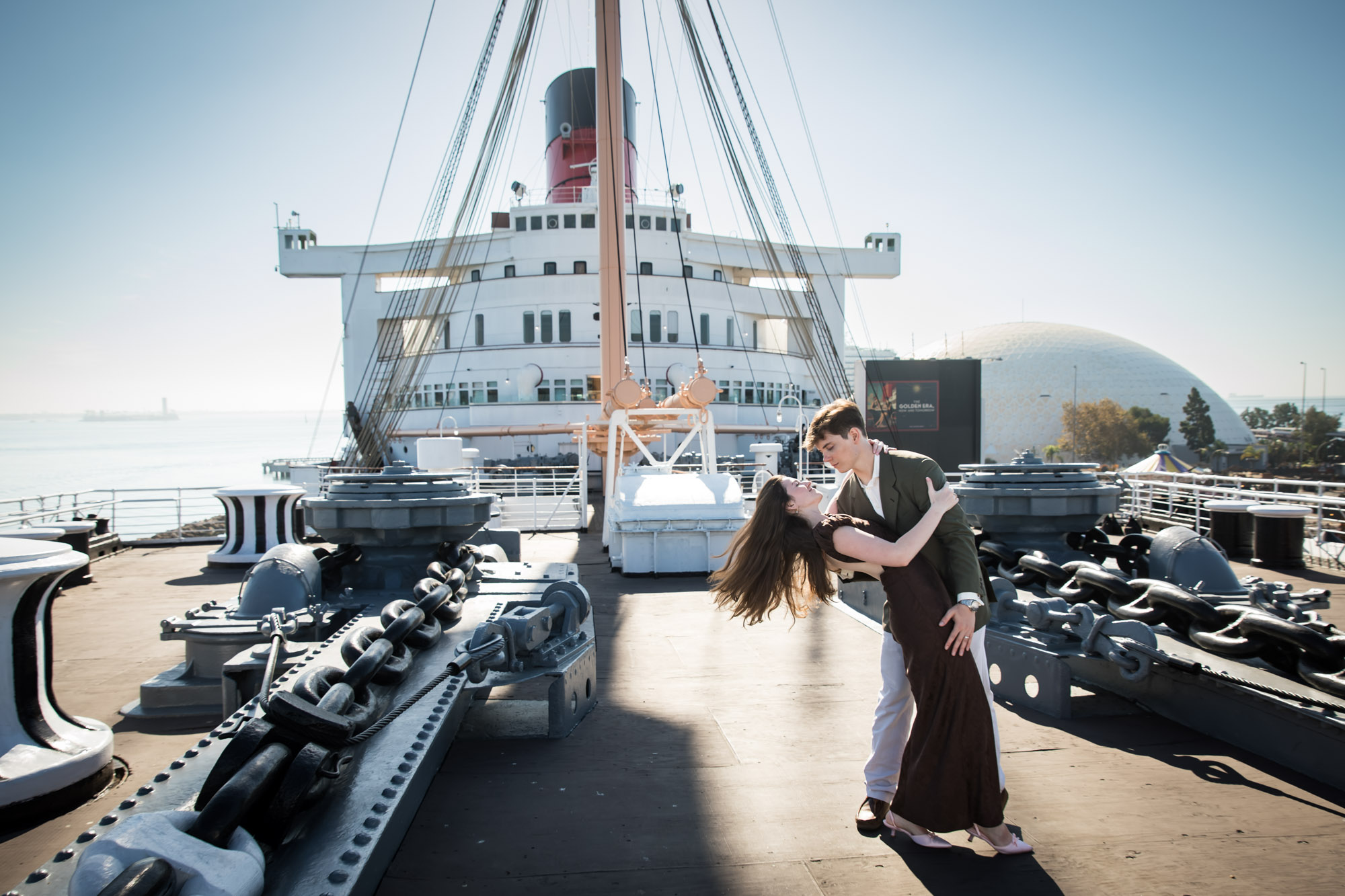 Man dipping his fiancée with her hair flying back on the Queen Mary's bow, Queen Mary photo shoot