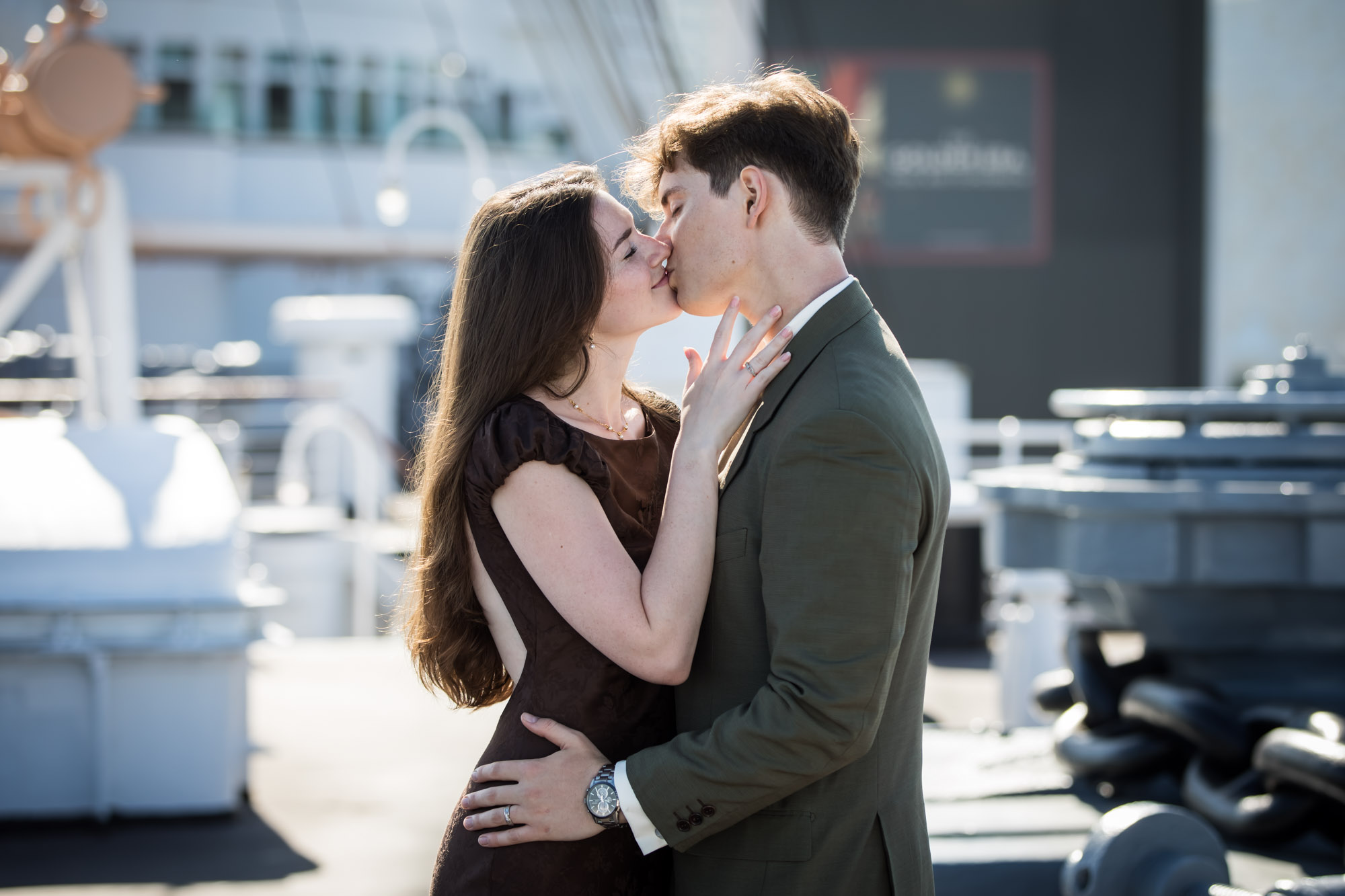 Couple sharing a kiss with her hand on his jaw and her engagement ring visible, Queen Mary photo shoot