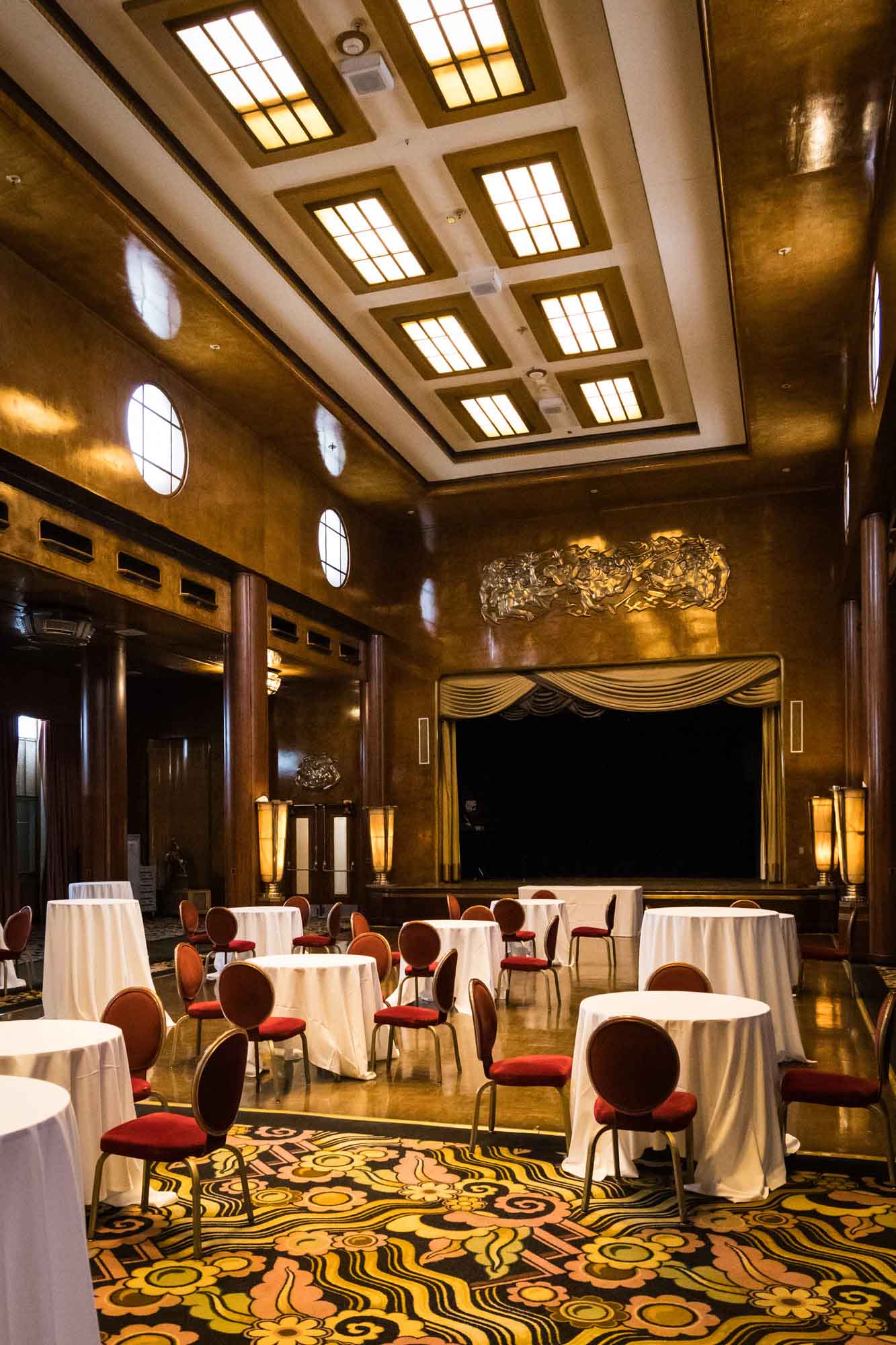 Art deco ballroom with a coffered ceiling, gold-toned walls, and a stage, ideal for a Queen Mary photo shoot