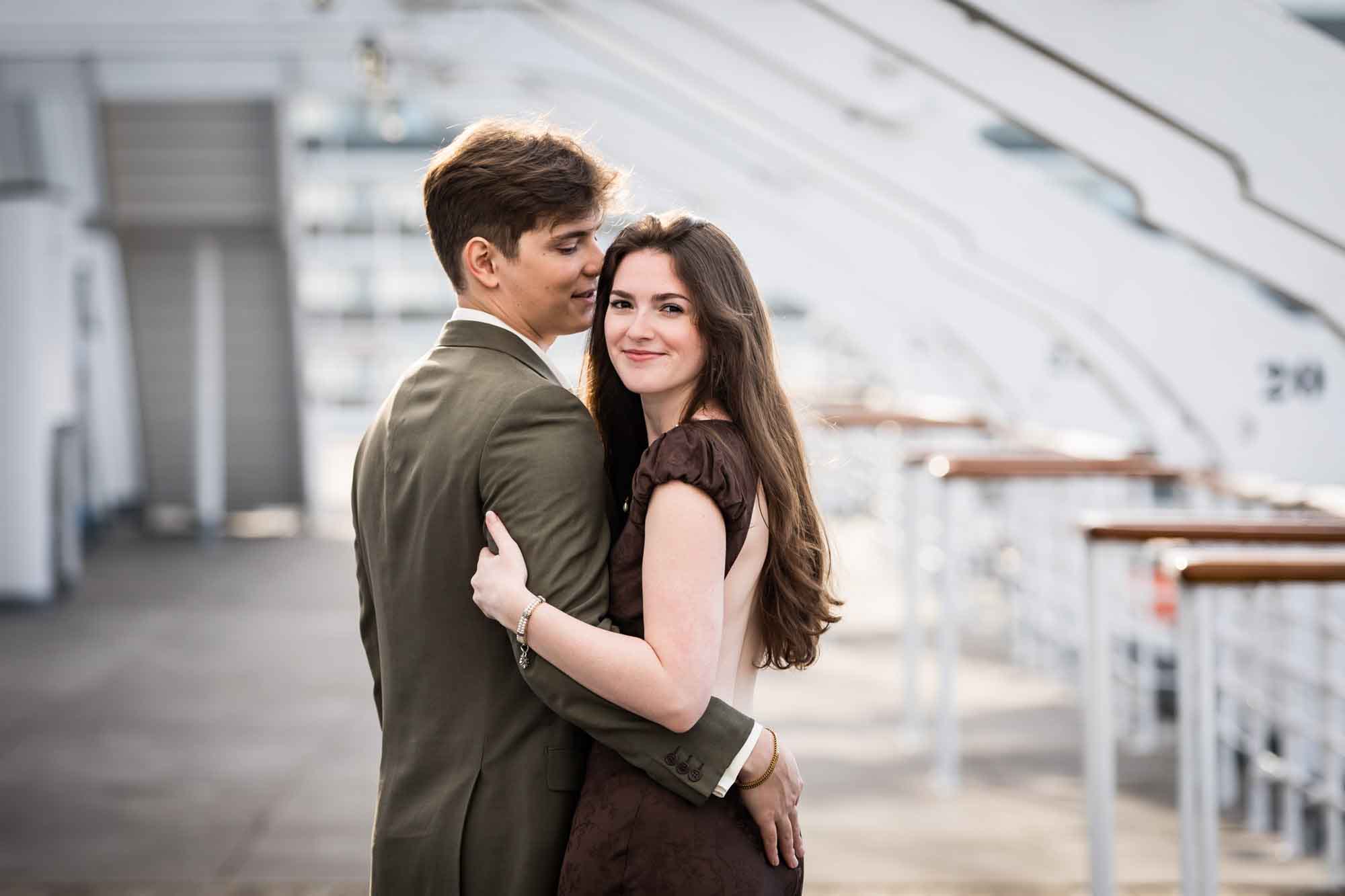 Woman smiling at the camera as she wraps her arms around the man on the Queen Mary deck, photographed by a Los Angeles photographer