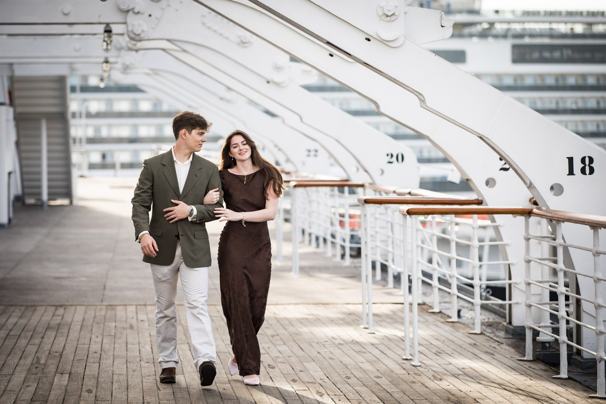 Couple smiling and walking arm in arm along the Sun Deck during a Queen Mary photo shoot