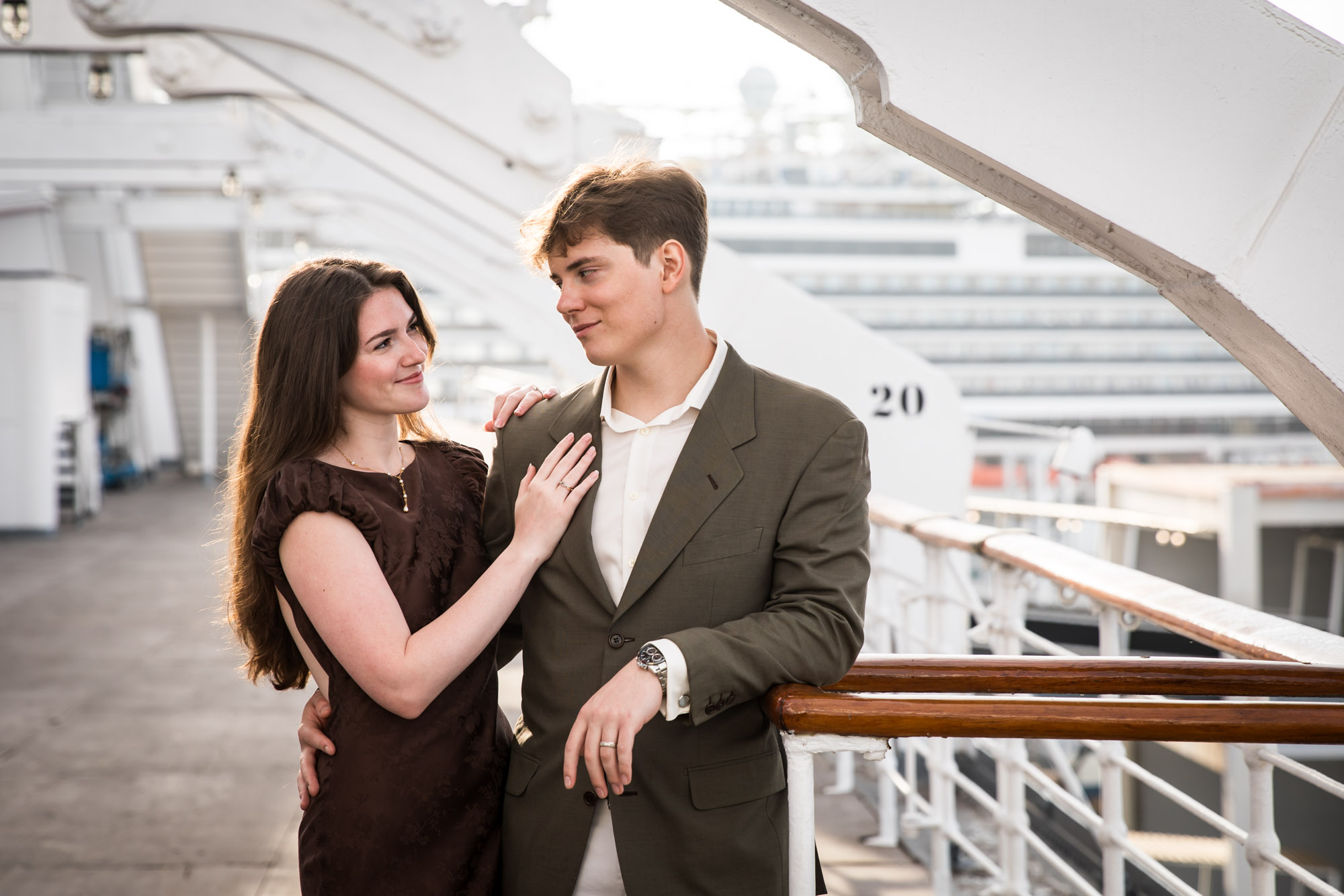 Couple gazing at each other beside a wood handrail during their Queen Mary photo shoot