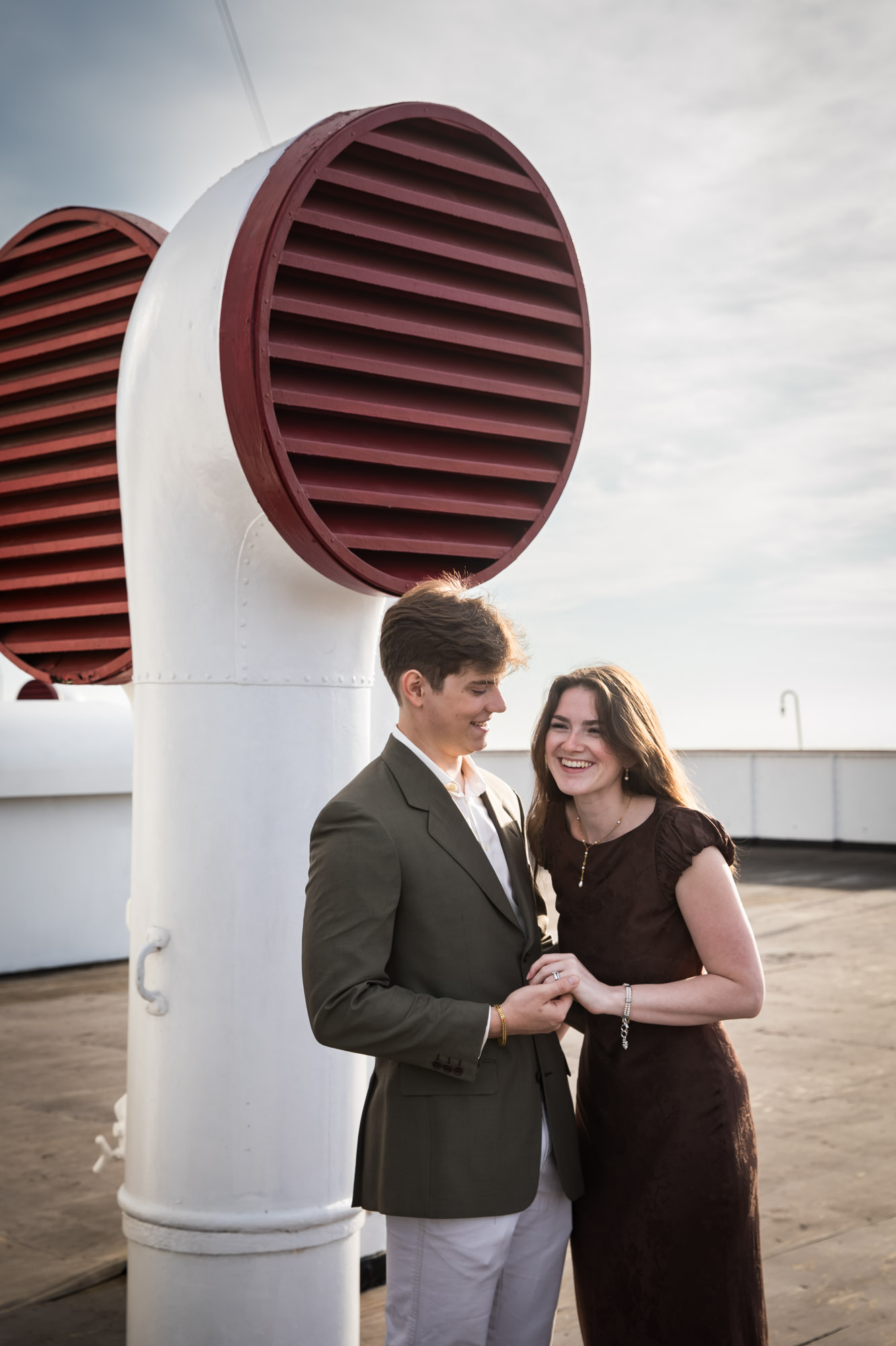 Couple holding hands and smiling beside a red louvered ventilator, photographed by a Los Angeles photographer