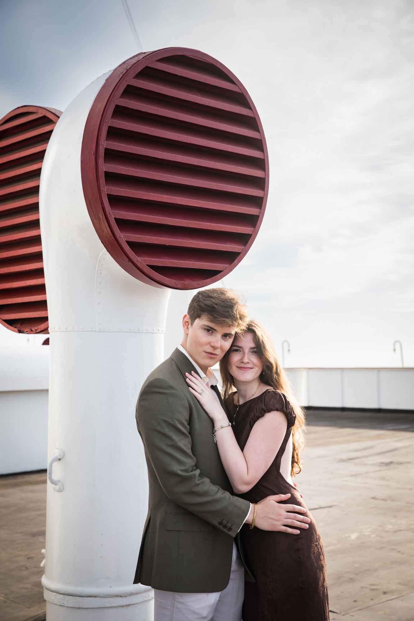 Couple embracing and looking at the camera beside a red and white ventilator, a Queen Mary photo shoot portrait