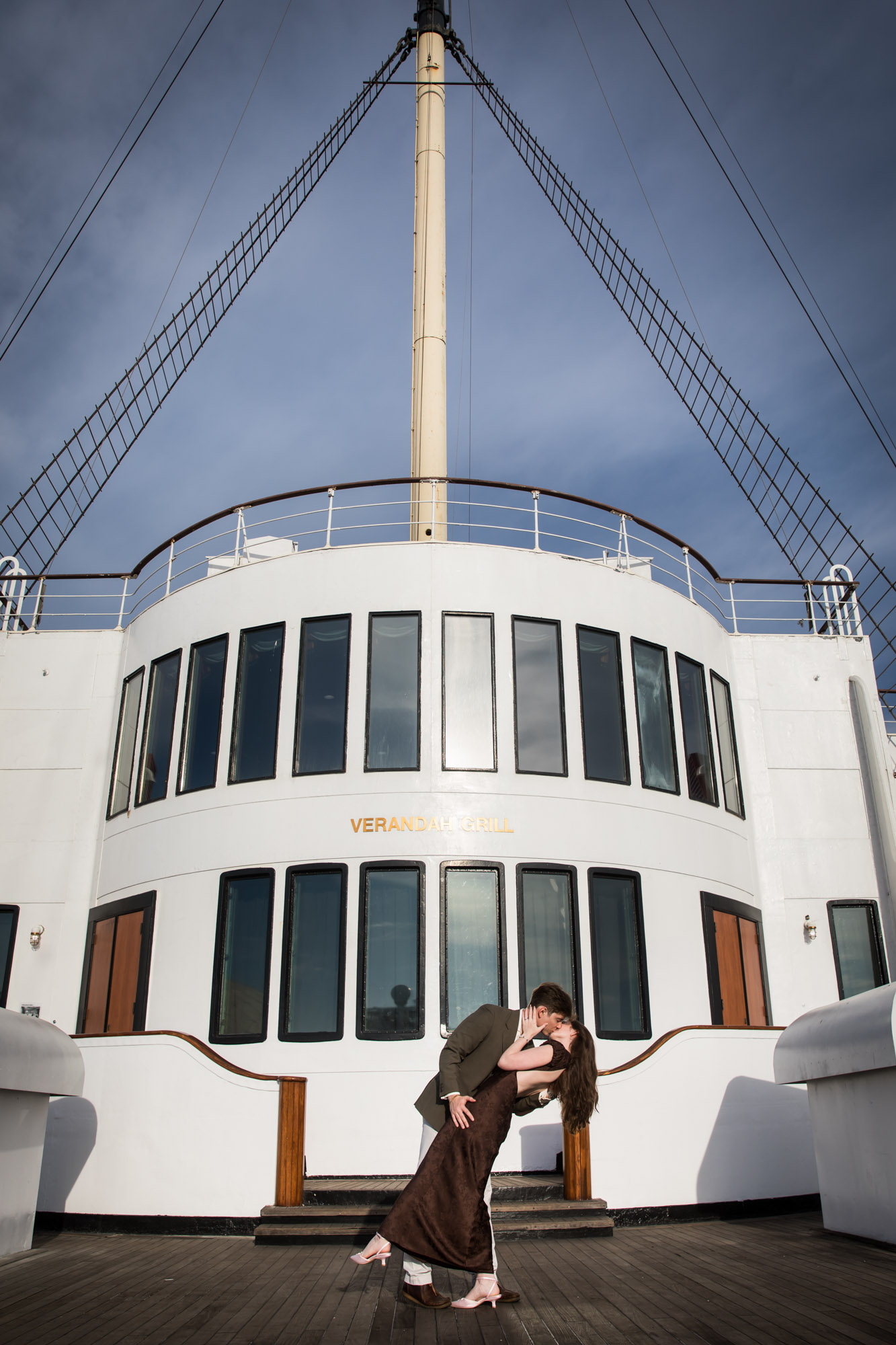 Couple sharing a dipped kiss in front of the Verandah Grill and mast on the Sun Deck during their Queen Mary photo shoot