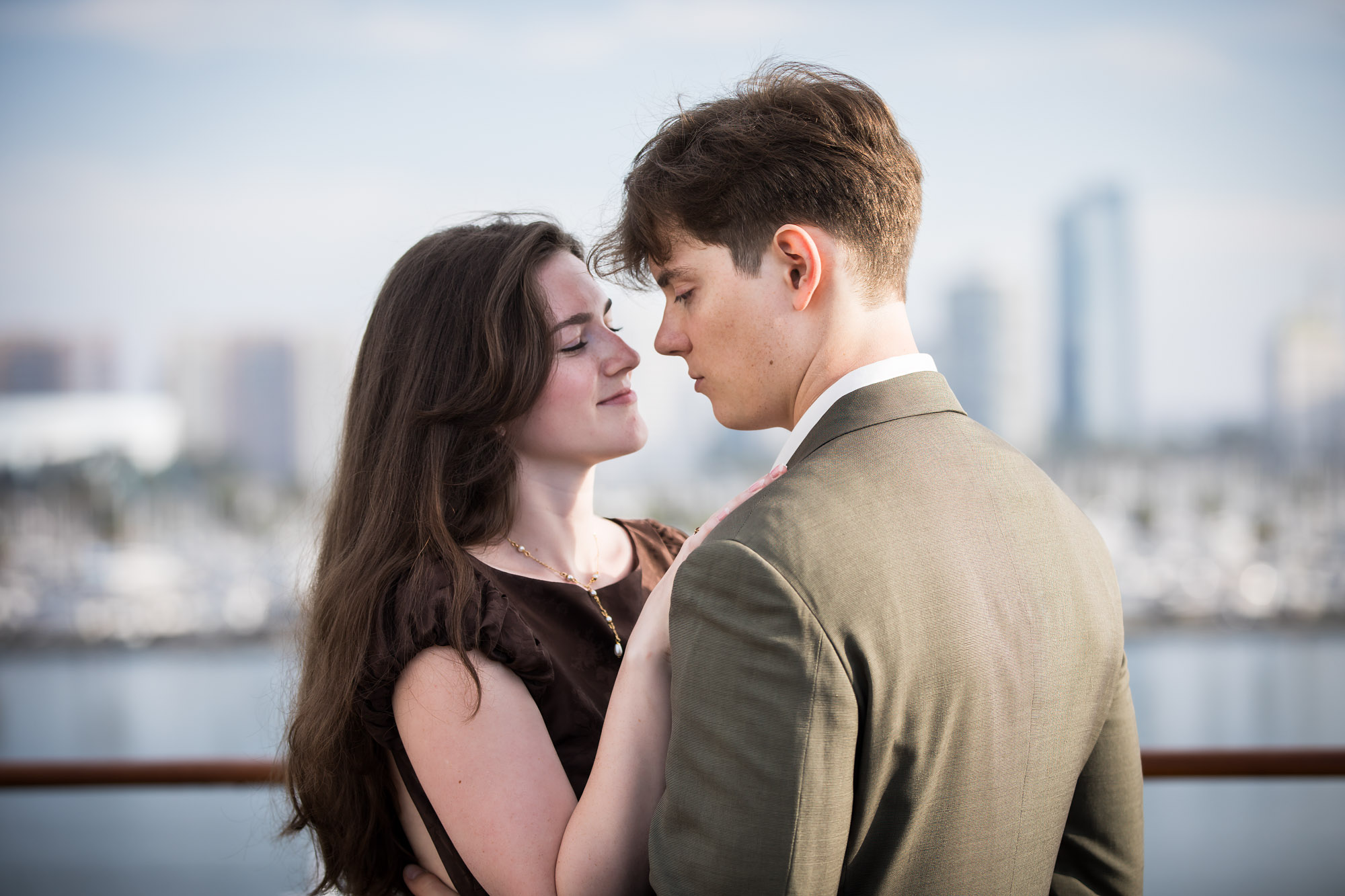 Couple nearly nose to nose with the blurred Long Beach skyline behind them, photographed by a Los Angeles photographer