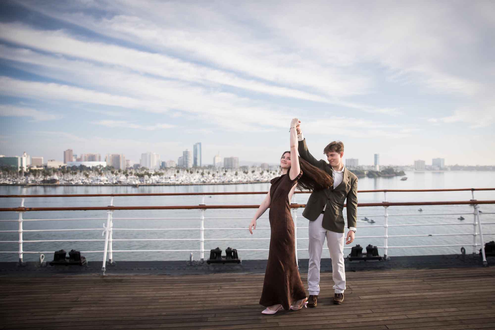 Man twirling the woman with her hair swinging, in front of the Long Beach skyline on a Queen Mary photo shoot