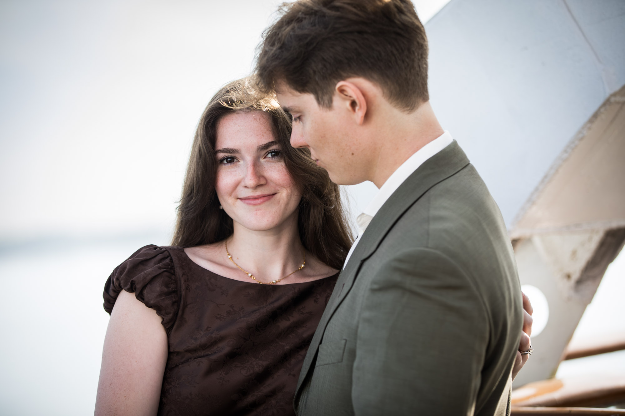 Close portrait of the woman smiling at the camera as the man looks down, on a Queen Mary photo shoot