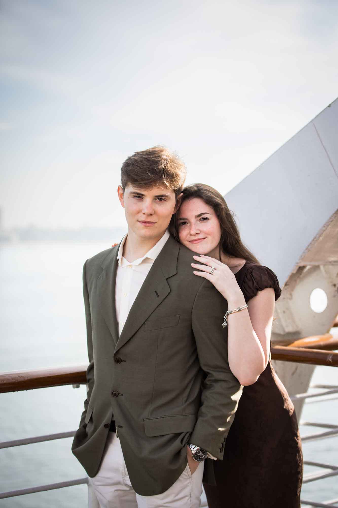 Man looking at the camera as the woman rests her head on his shoulder at the rail, a Queen Mary photo shoot portrait