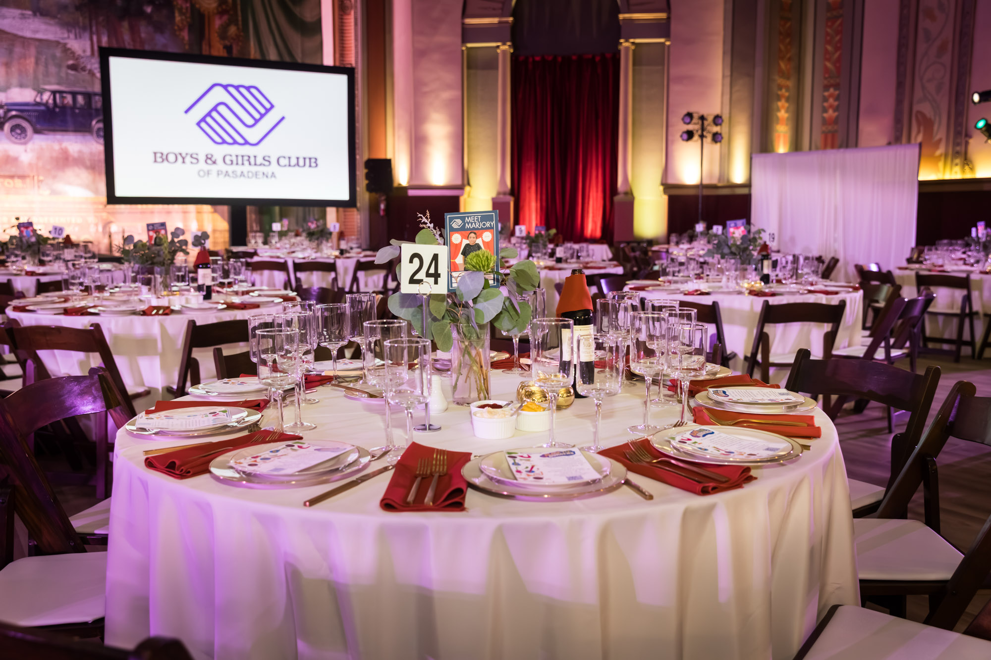 Raymond Theatre photos of a dinner table set in red and white with a Boys & Girls Club of Pasadena logo screen