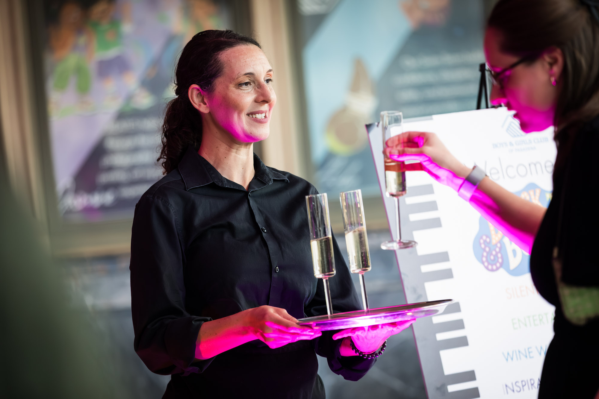Los Angeles event photographer shot of a server offering champagne by the welcome sign as a guest takes a glass