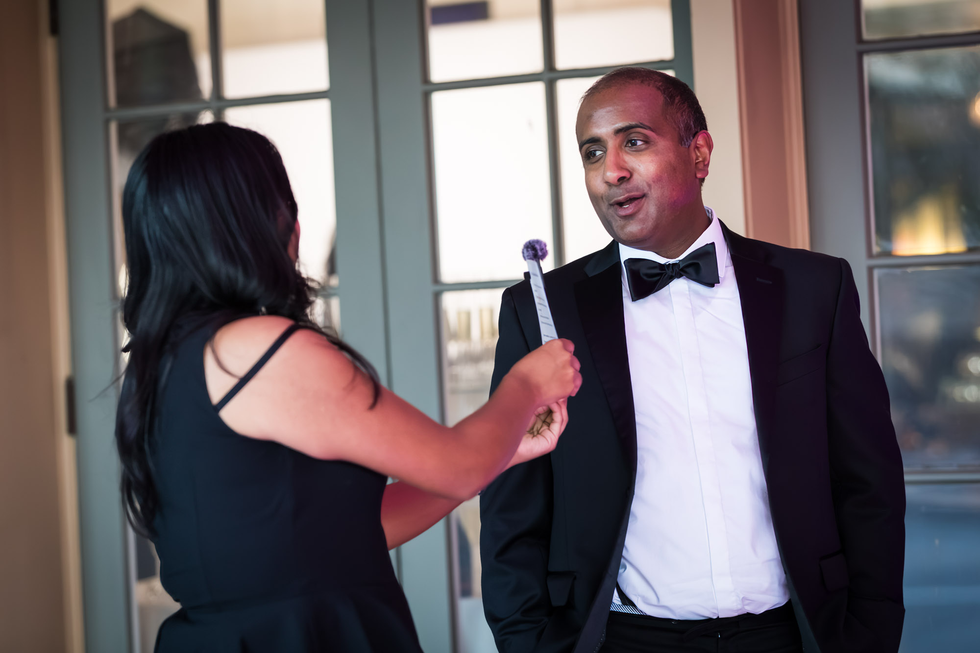 Raymond Theatre photos of a guest in a tuxedo and bow tie chatting during the cocktail reception