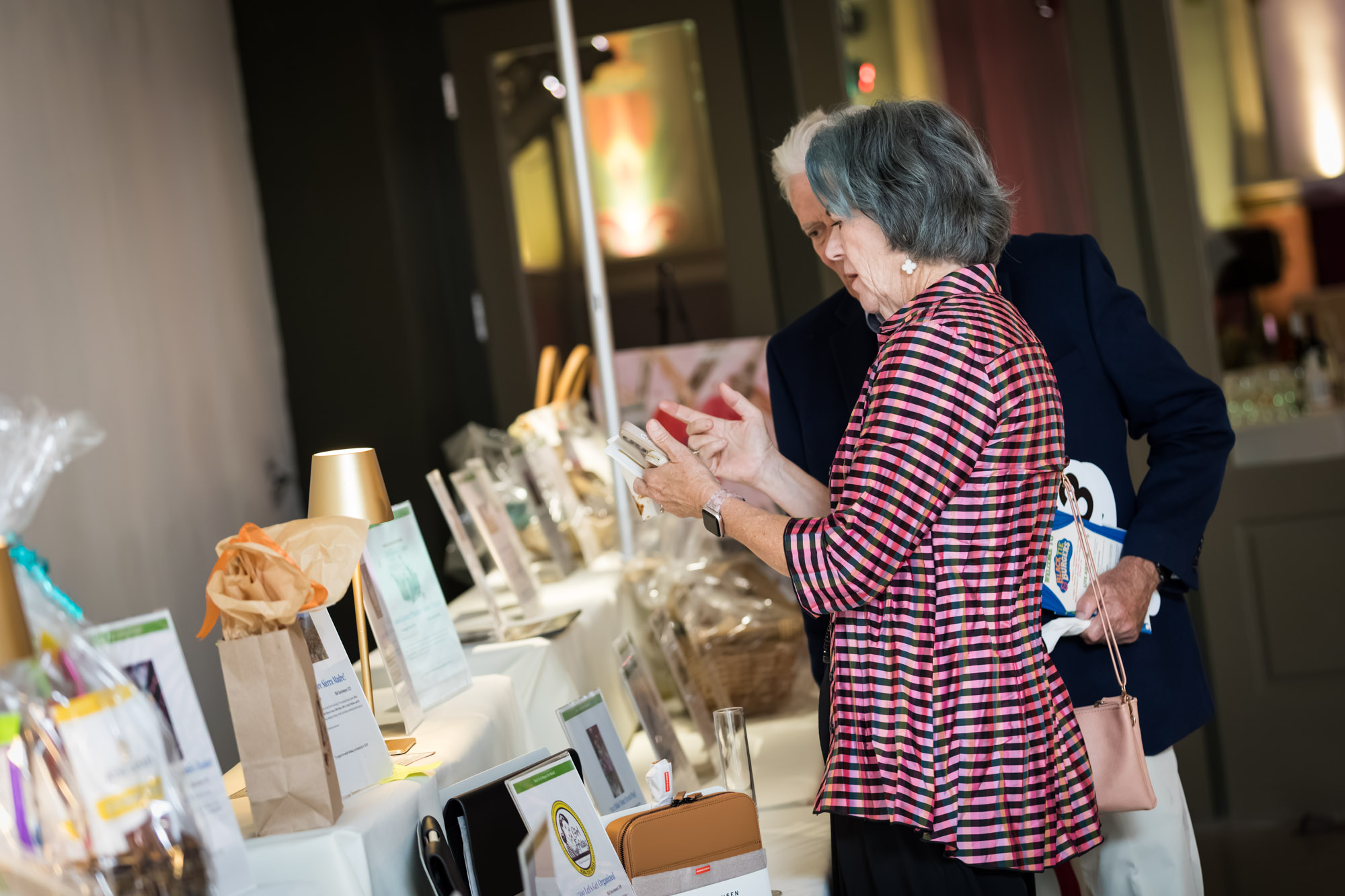 Los Angeles event photographer image of guests browsing silent auction gift baskets and bid sheets