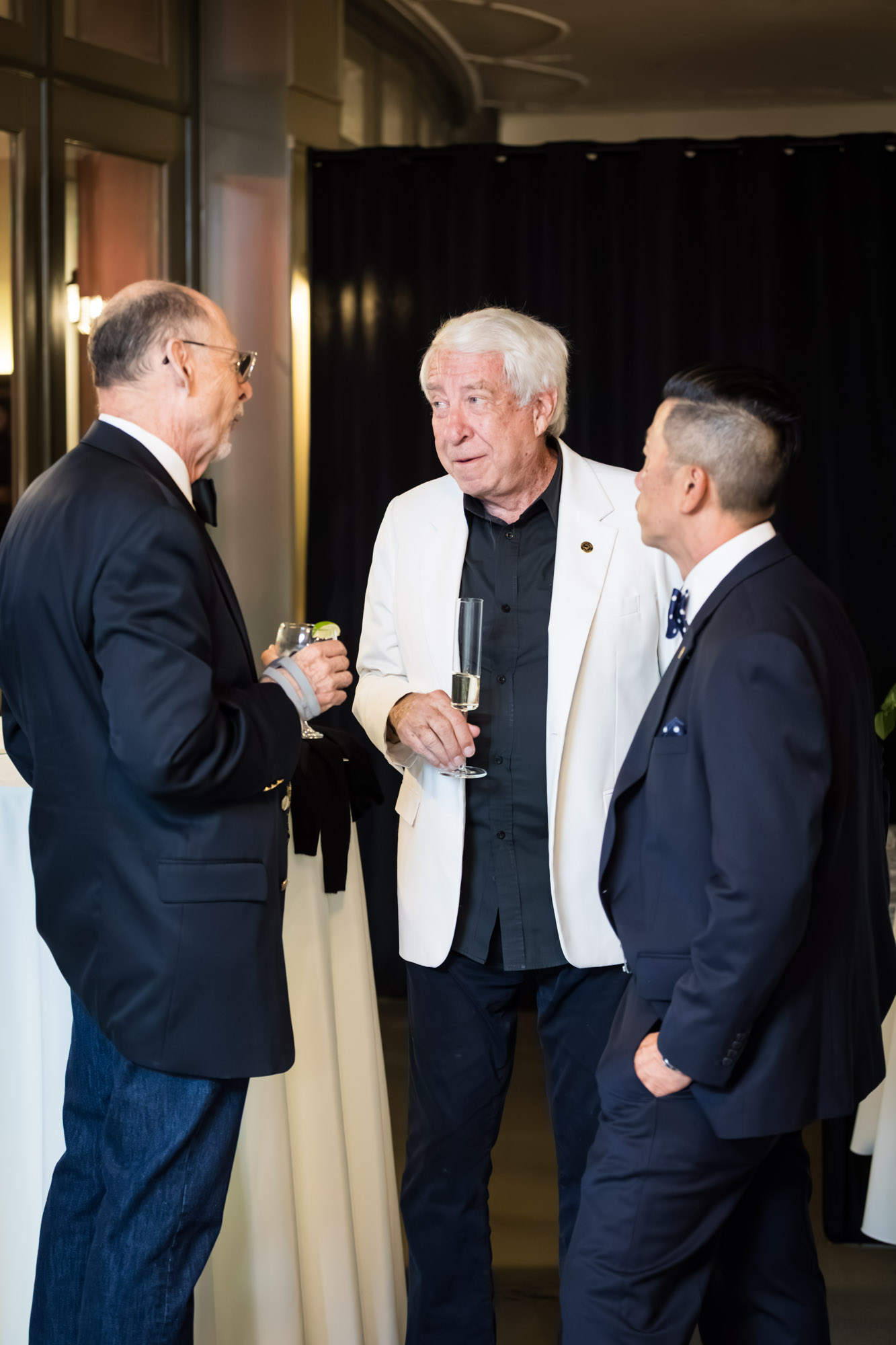 Los Angeles event photographer candid of three men in blazers chatting over drinks at the cocktail hour