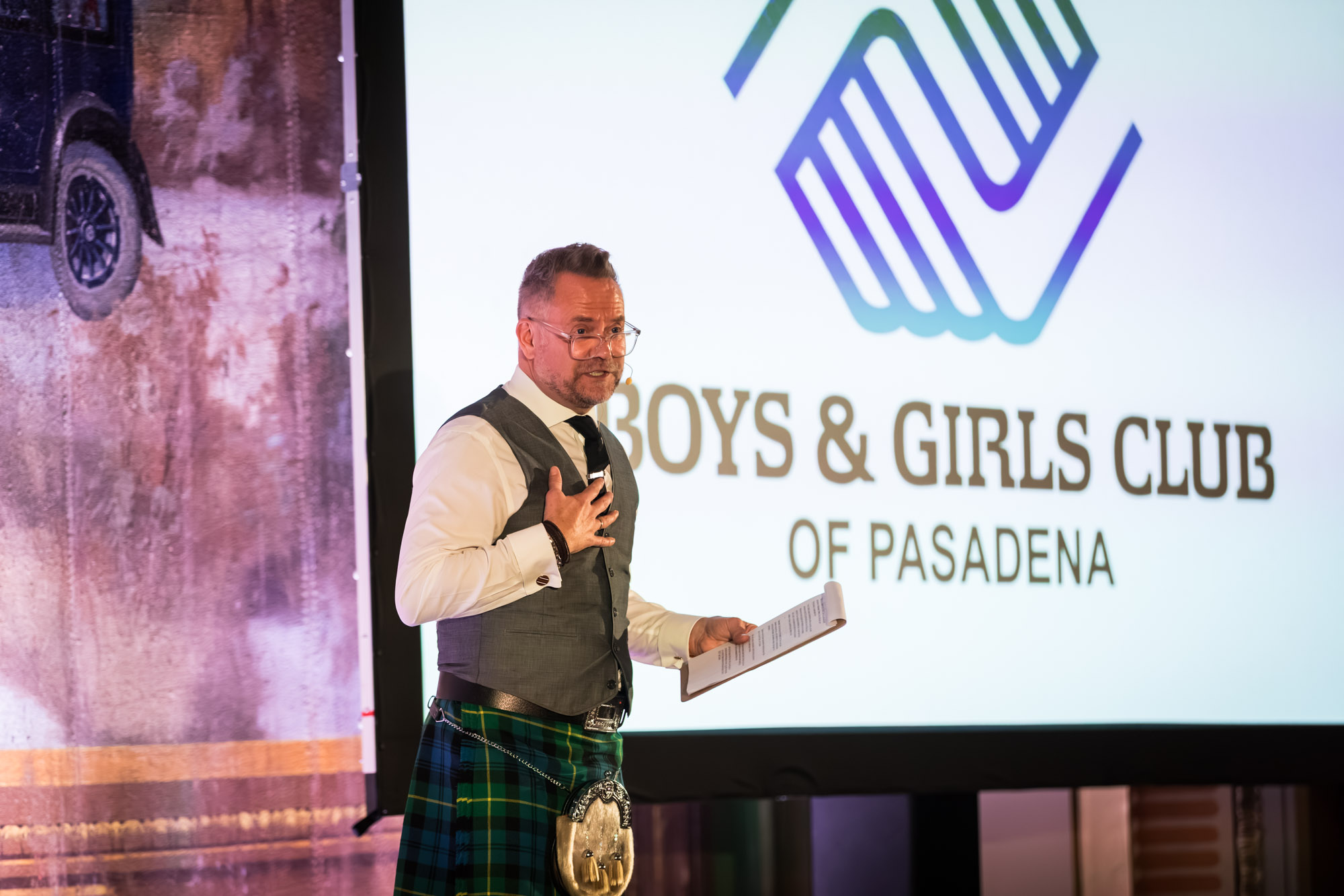 Los Angeles event photographer shot of a speaker in a kilt and vest with a hand on his chest, holding notes