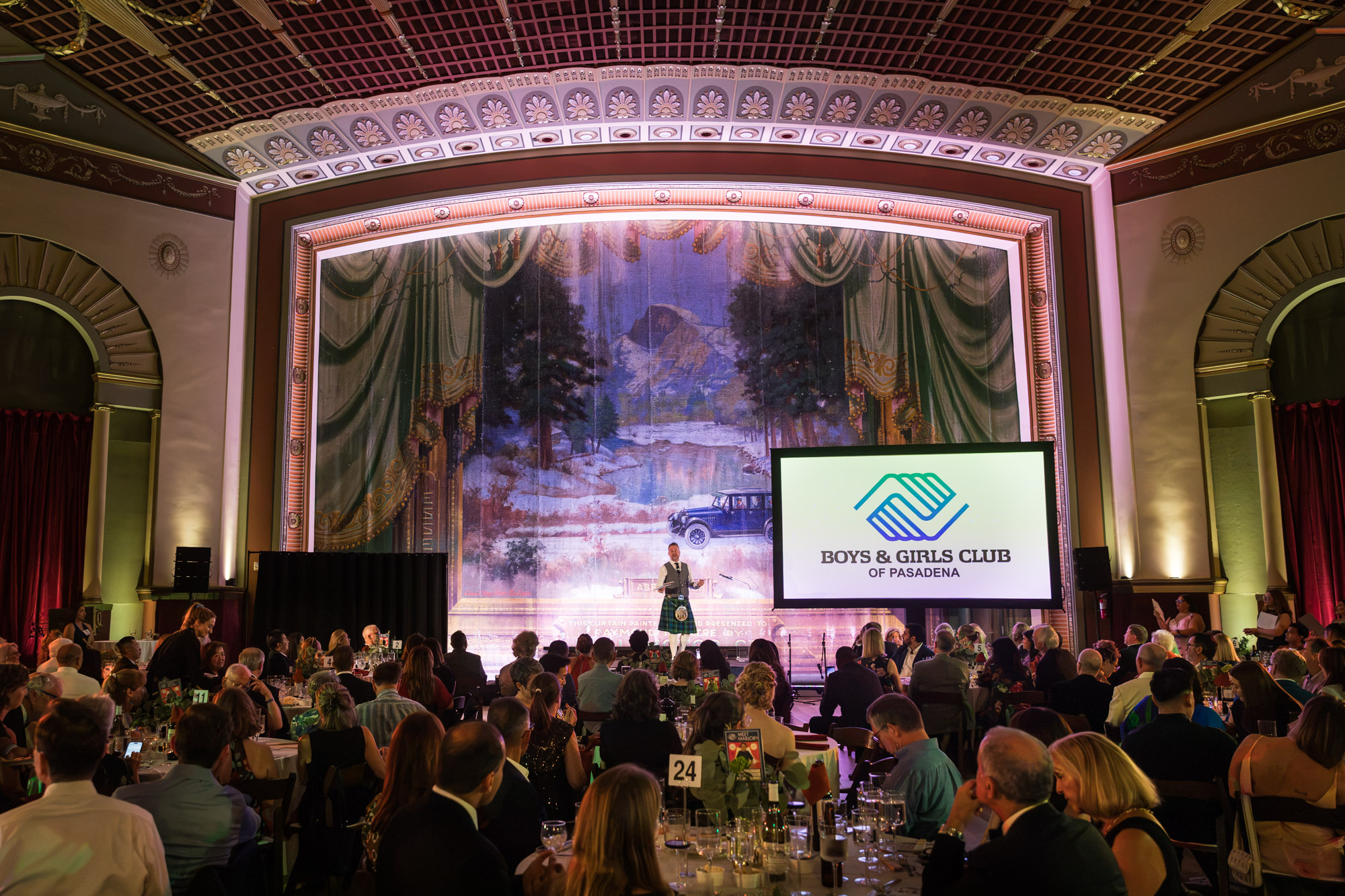 Raymond Theatre photos: wide view of the coffered ceiling, painted curtain, and full tables during the program