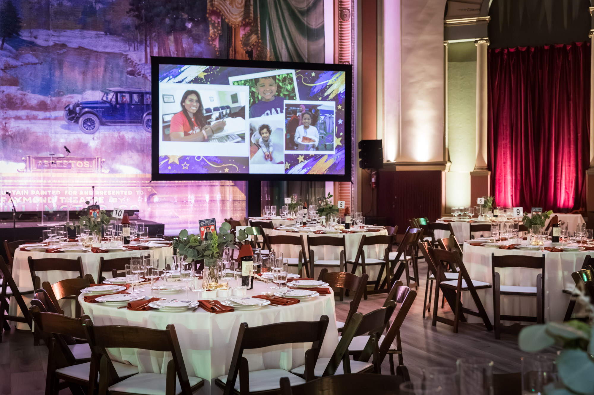 Raymond Theatre photos of dinner tables and a screen of smiling kids in front of the painted stage curtain