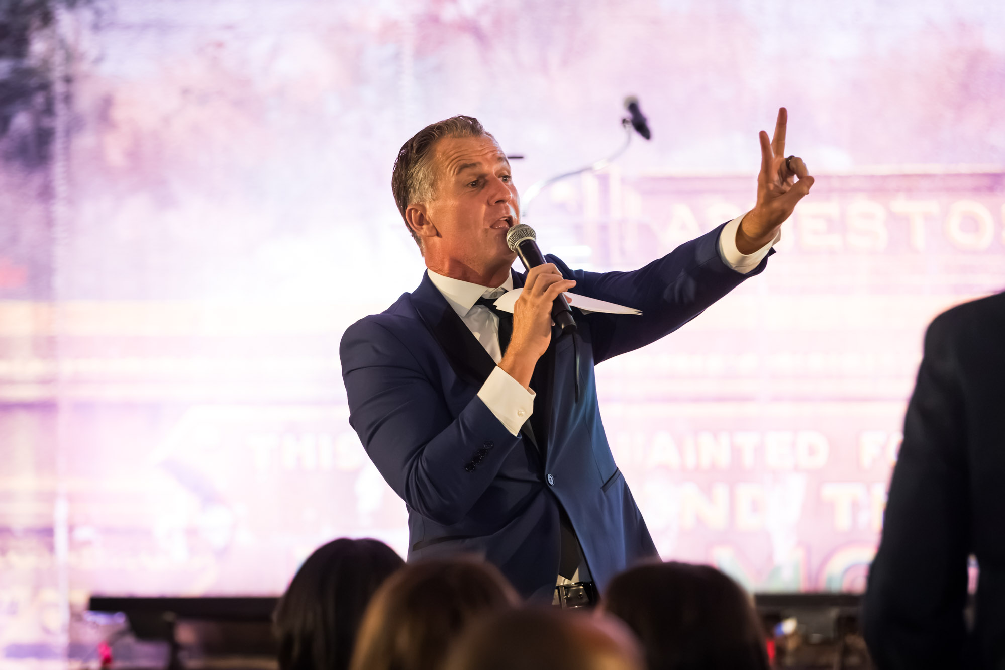 Los Angeles event photographer shot of a speaker holding up two fingers and a microphone on stage