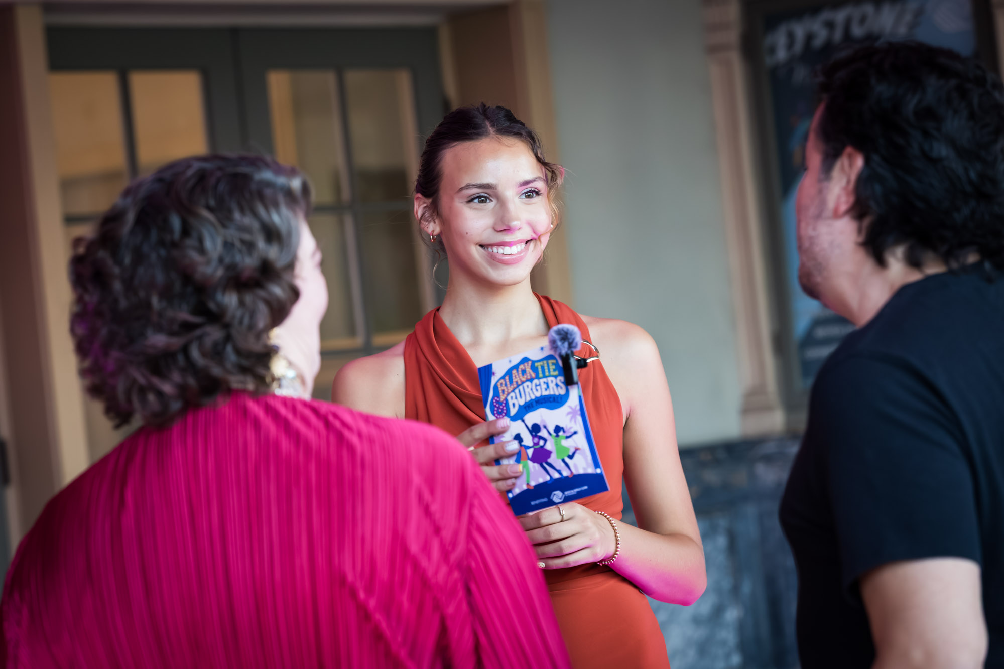Los Angeles event photographer capturing a smiling greeter handing a Black Tie & Burgers program to guests